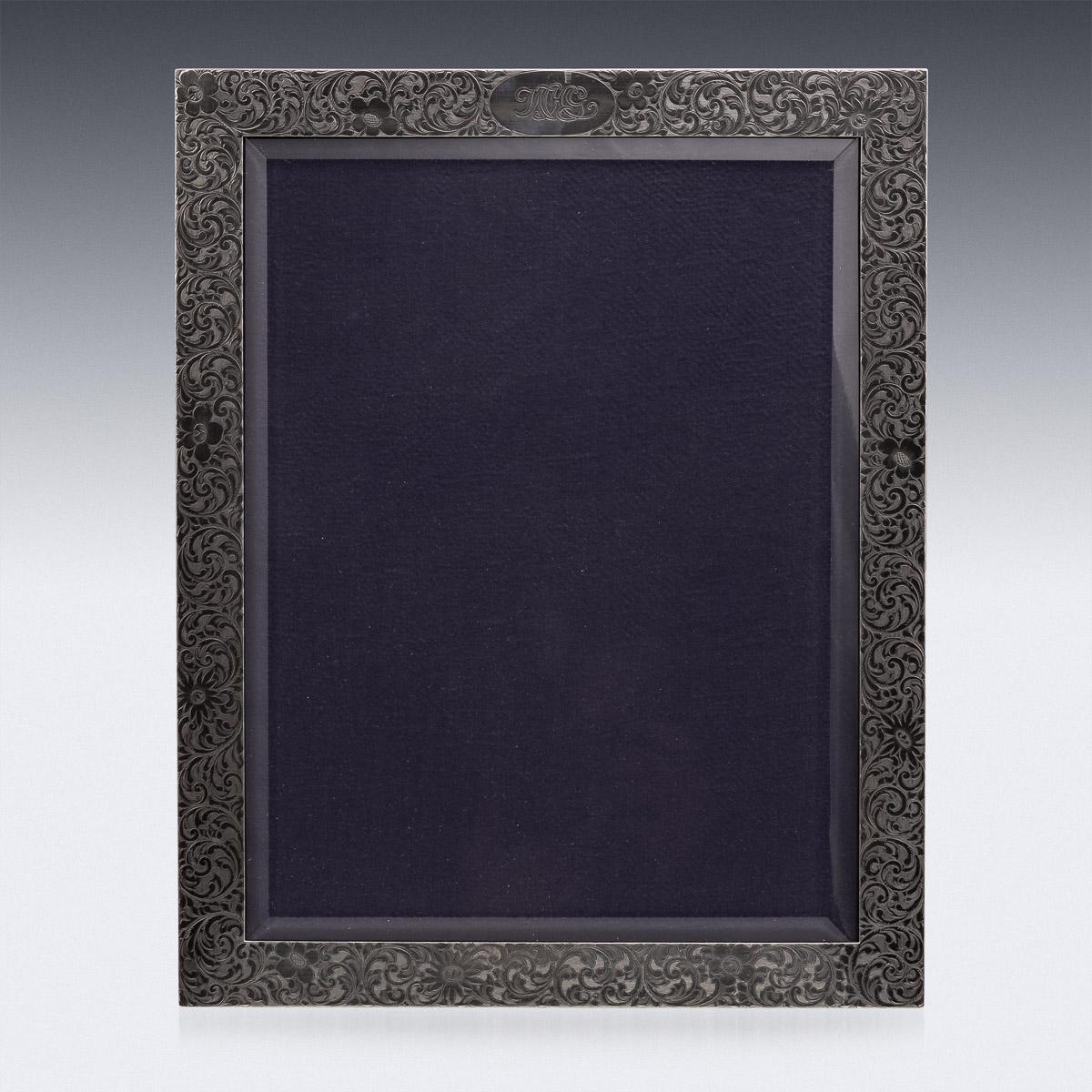 Antica cornice fotografica americana in argento massiccio dei primi del Novecento, particolarmente grande, incisa con volute e fiori, la parte superiore con le iniziali WHG, montata su un retro in legno con supporto a cavalletto, la parte anteriore