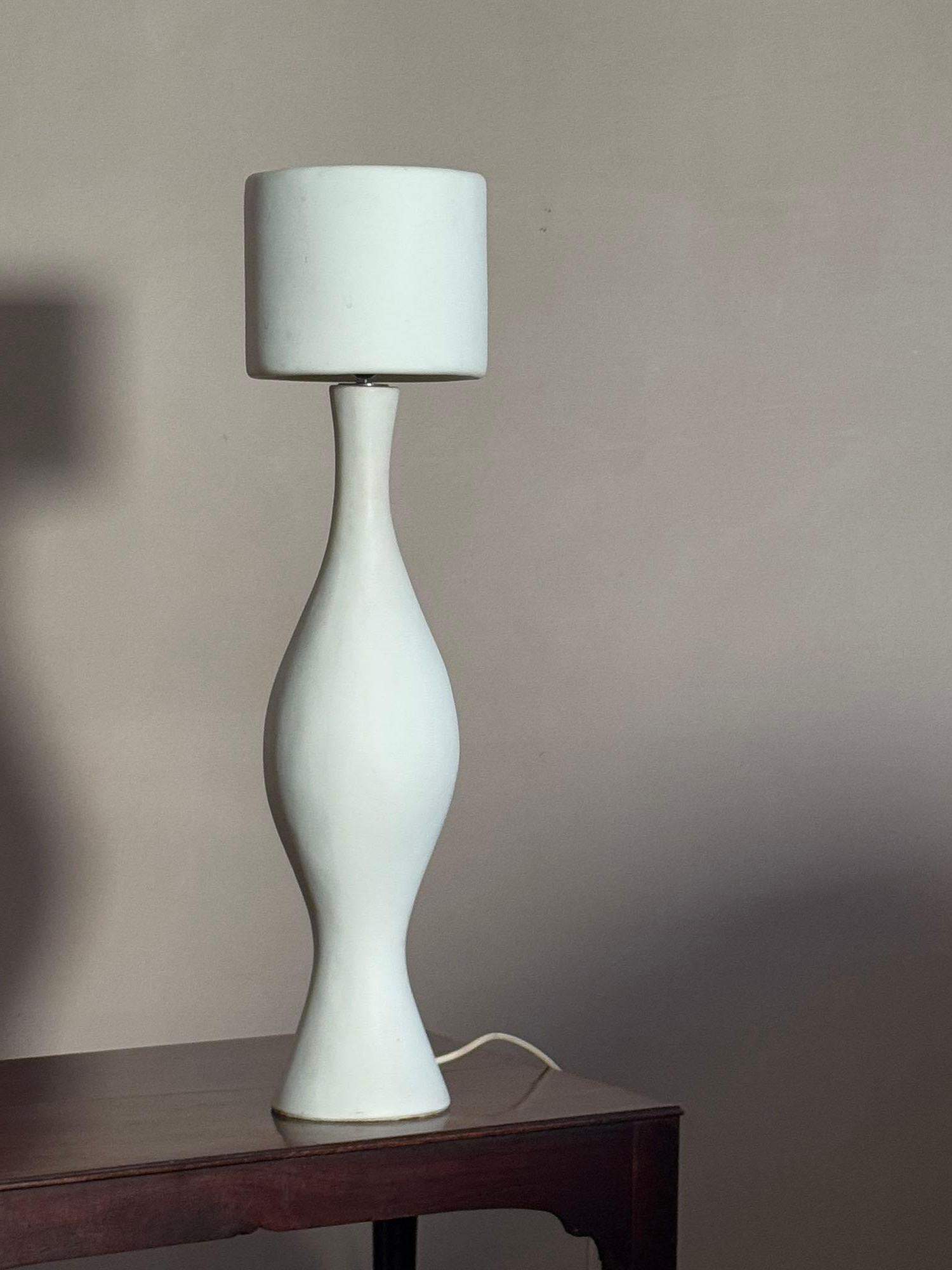 A sculptural baluster form white ceramic lamp with shade. Signed with an unknown makers mark, vaguely similar to lamps by Georges Jouve Dimensions; H 75cm
W shade 19cm
W base 15cm