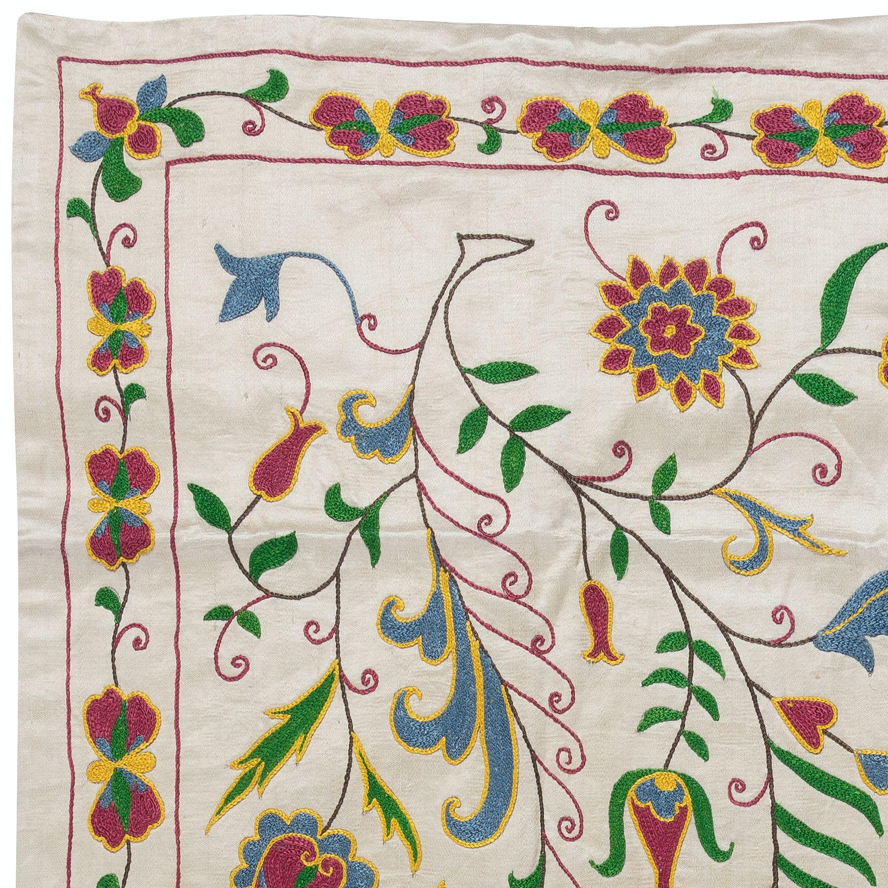 Unser exquisiter, handbestickter Wandbehang aus 100 % Seide von Suzani ist ein fesselndes Stück, das Kunst und Funktionalität nahtlos miteinander verbindet. Dieser atemberaubende Dekorationsartikel ist sowohl ein Wandteppich als auch eine Decke und