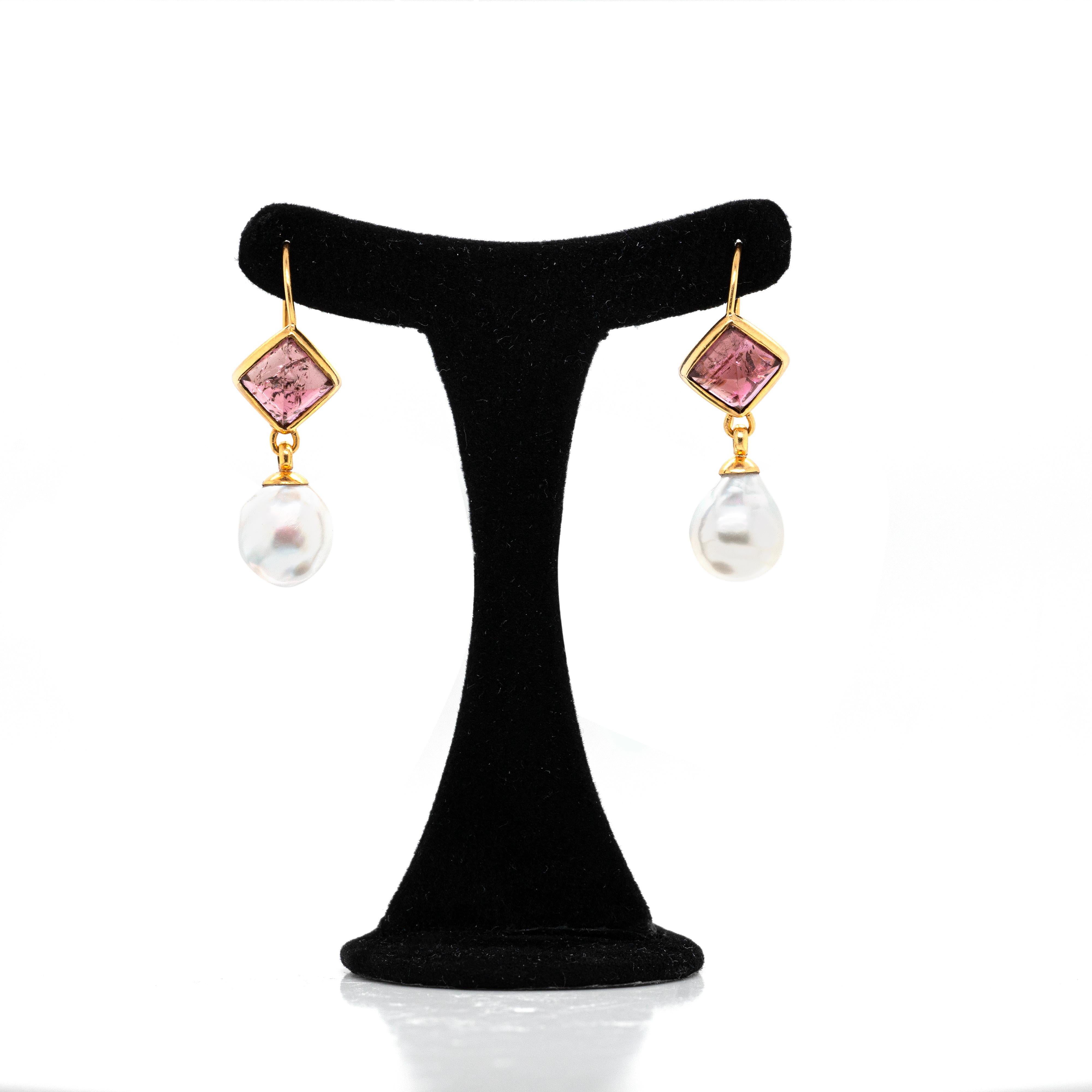 These wonderful 21 carat yellow gold drop earrings feature each a 10.5 x 10.5 mm pyramid cabochon tourmaline, mounted in rub-over square settings. The earrings are then finished with carefully paired baroque South Sea pearls measuring approximately