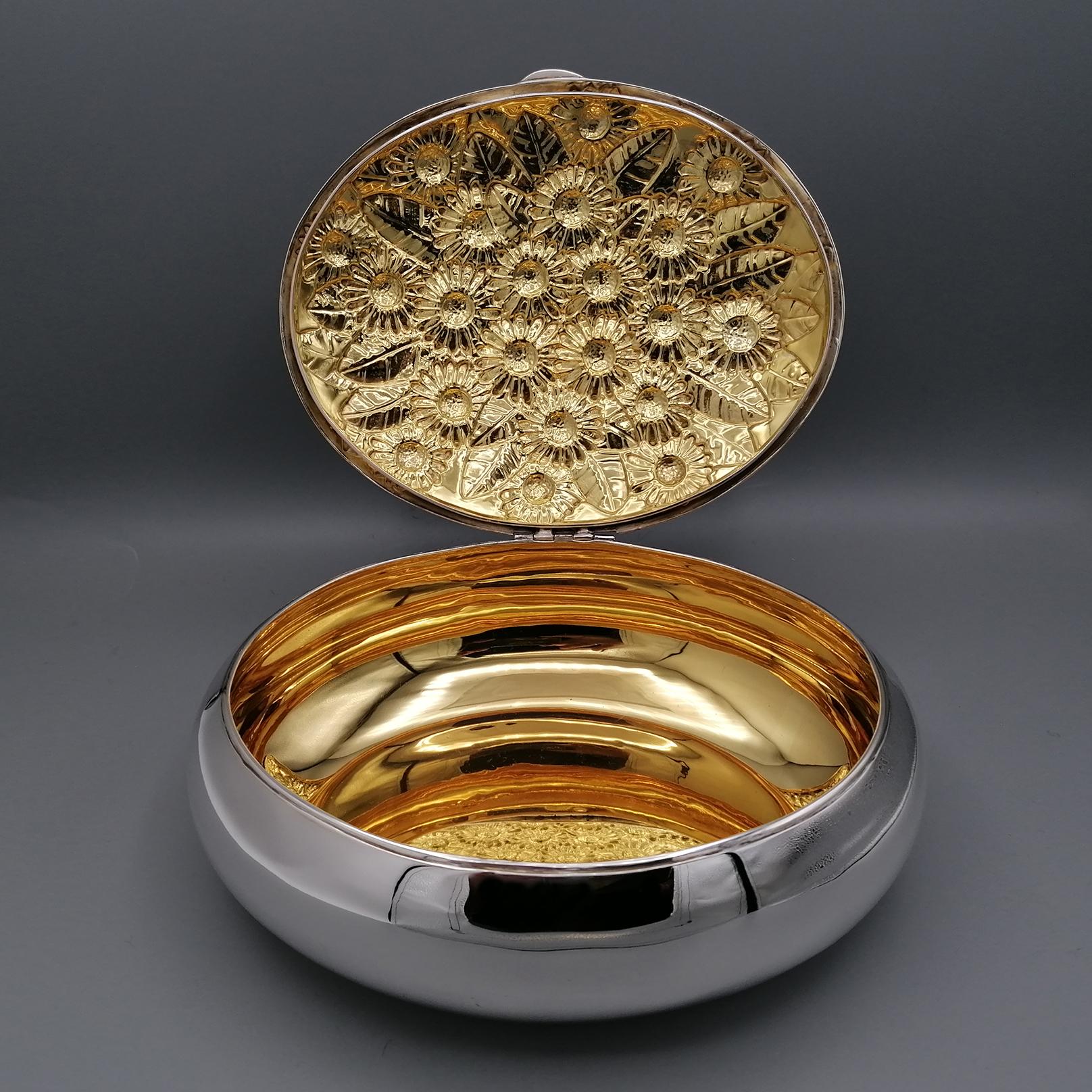 Oval box in solid 800 silver with embossed daisies and 24kt golden interior.
This box was made entirely by hand giving it an oval shape.
The lid, finely embossed with flower motifs and specifically daisies, was hinged creating a single piece