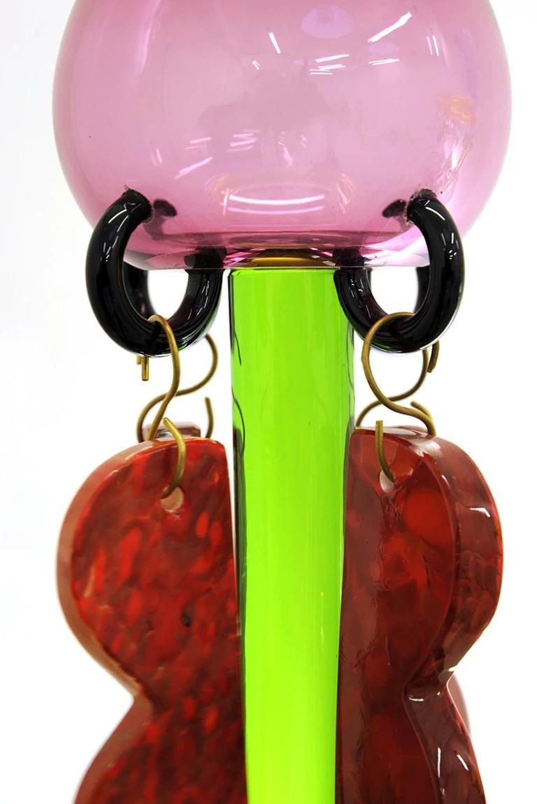Die Glasvase Clesitera mit Hängeleuchte wurde 1986 von Ettore Sottsass entworfen. Die Vase ist aus mundgeblasenem Glas und auf dem Sockel signiert. Weitere Informationen finden Sie in der unten stehenden Authentizitätsinformation. 

Ettore Sottsass