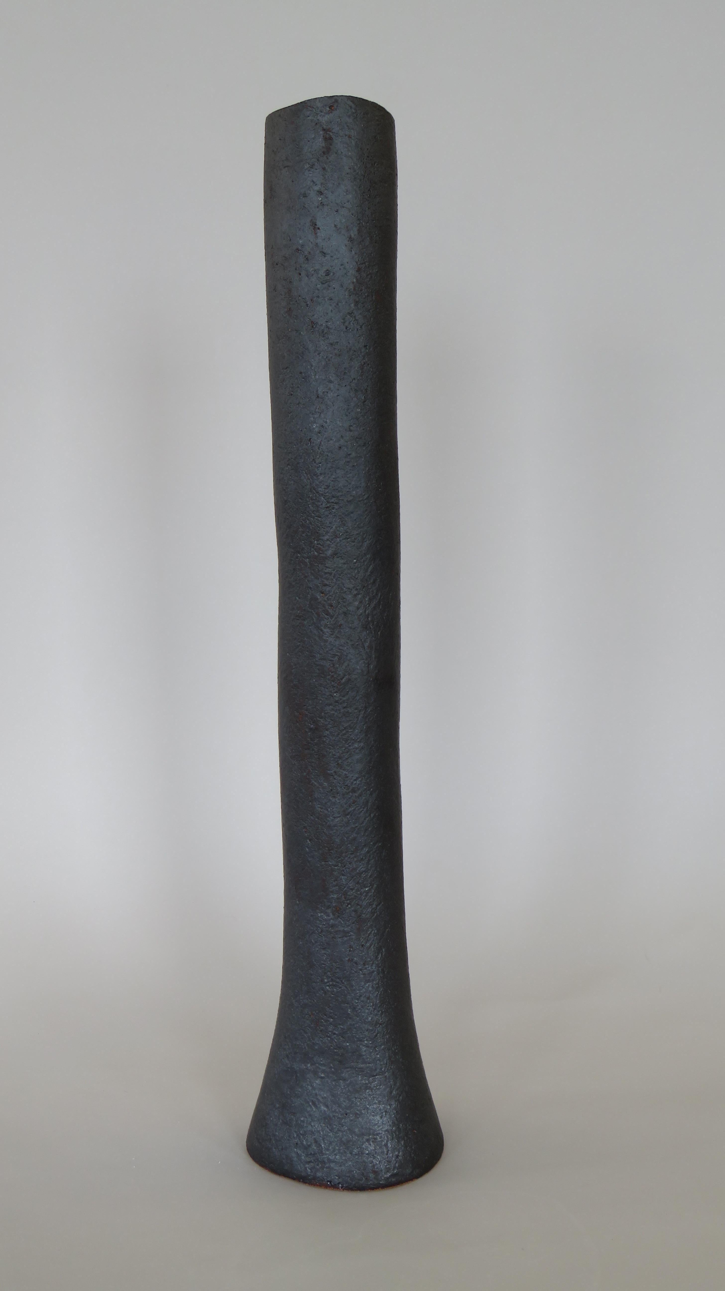 These tall vases in a metallic black glaze over stoneware are weighted on the bottom for tall floral arrangements or branches. Each surface is scraped to show the texture and tone of the clay, with varying bases or knobby edges. The top rims are