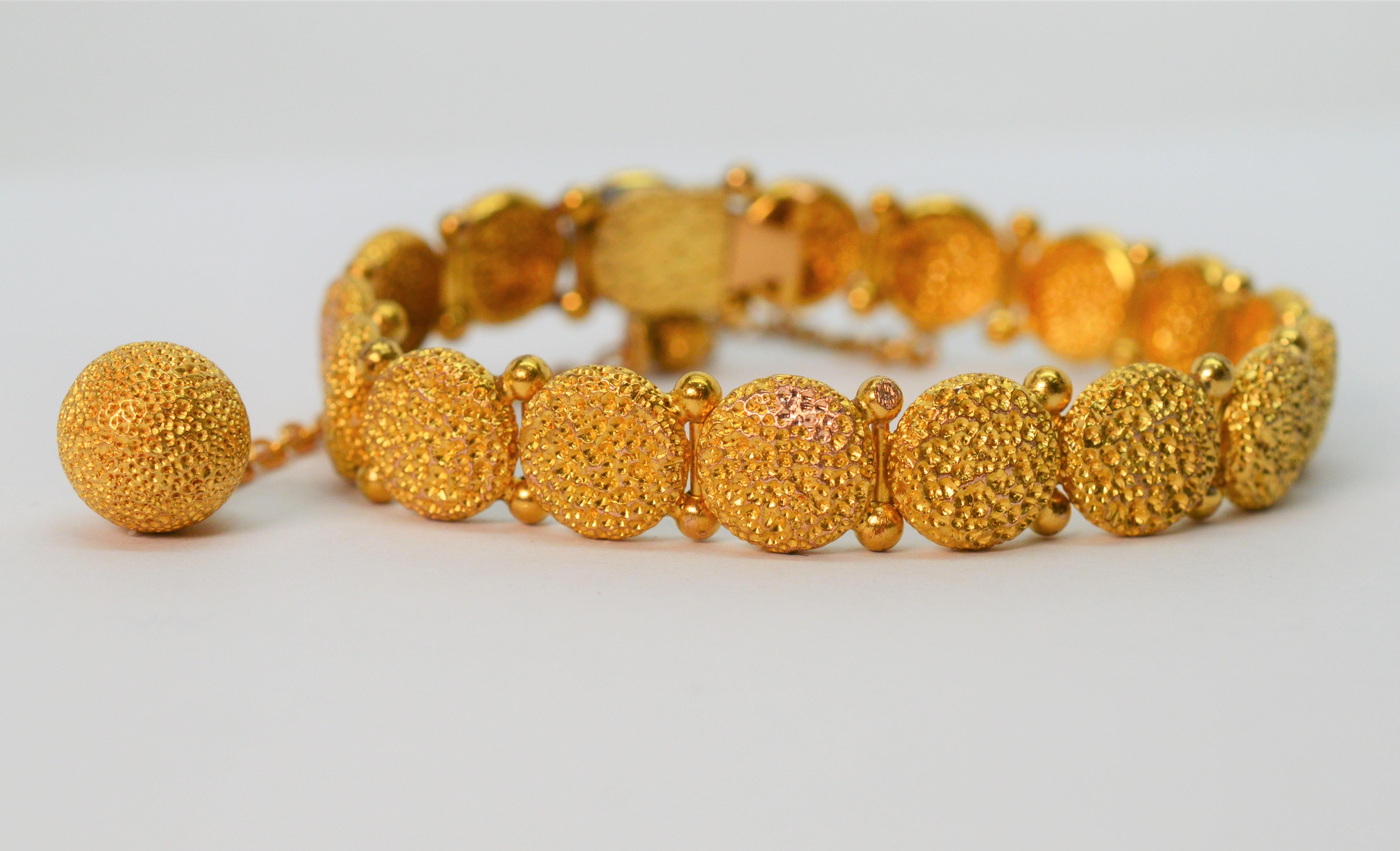 Unique texture is displayed on this rich twenty one karat 21K yellow gold bracelet through the artisan's sand casting. Seventeen individual links joined with decorative hinges create it's 6-3/4 inch length. A matching decorative gold ball charm