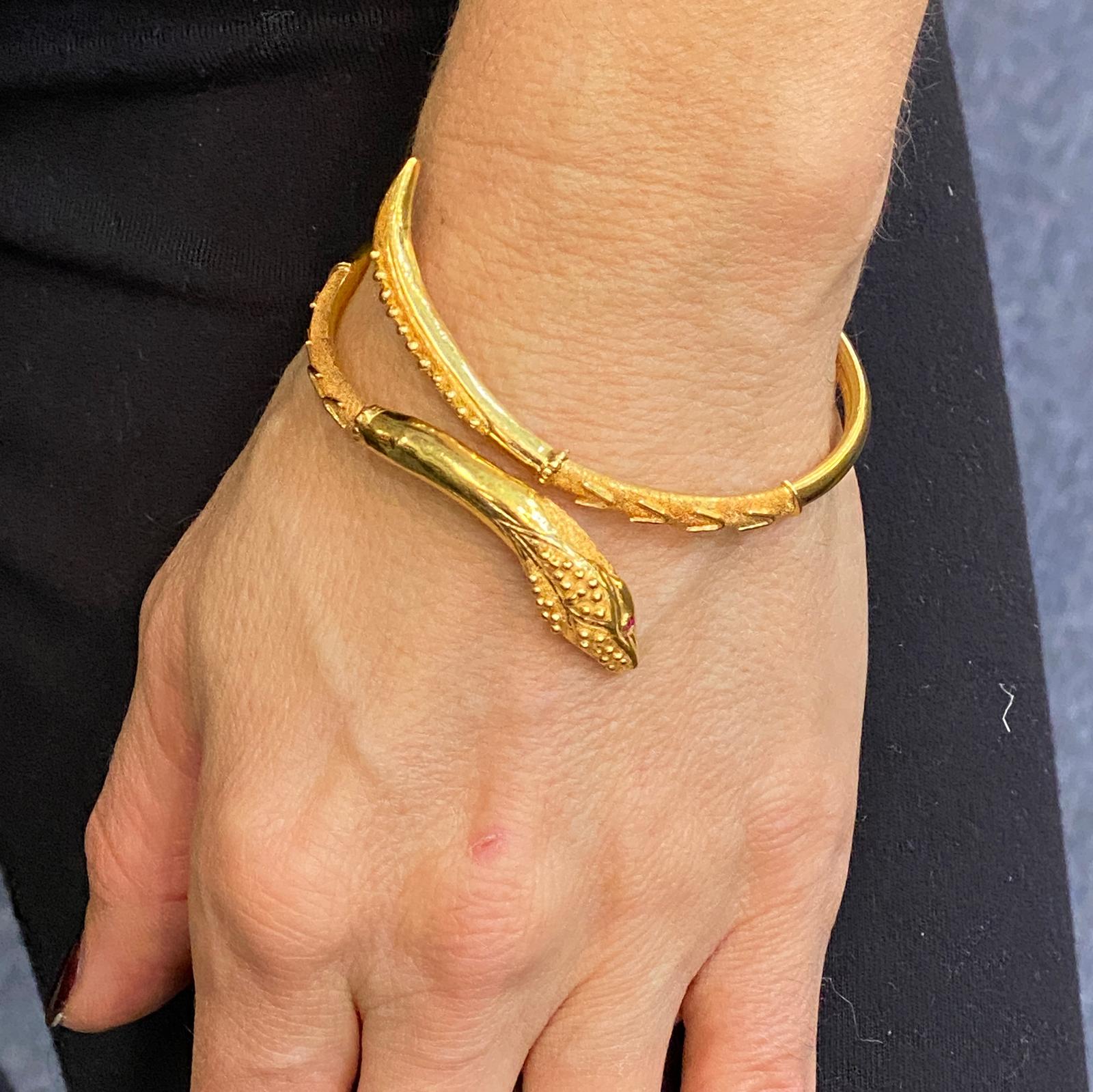 Fabulous cuff snake bracelet fashioned in 21 karat yellow gold with ruby eyes. The bracelet measures approximately 7 inches in internal circumference, and 2.25 inches in diameter. 