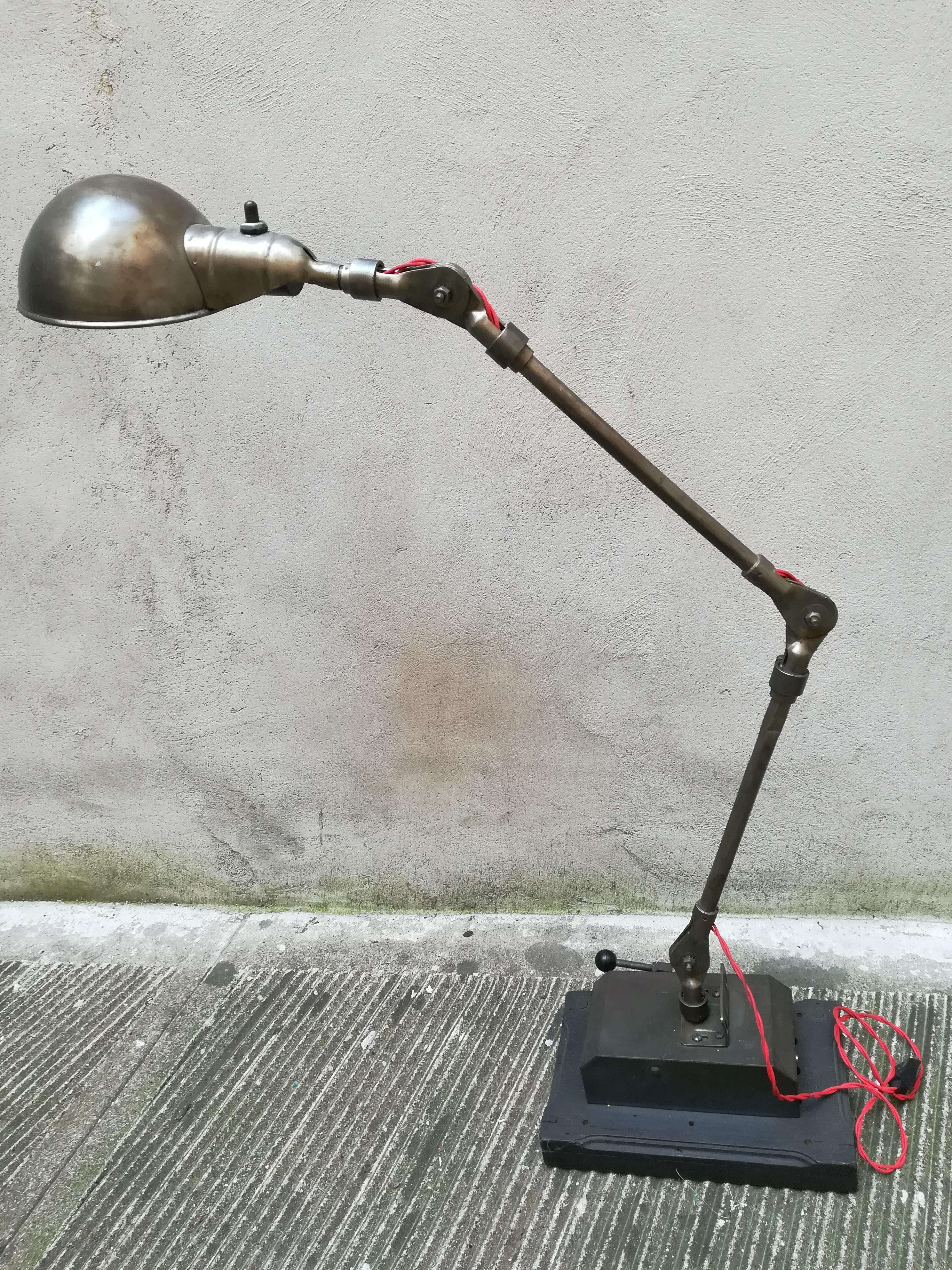 This beautiful upcycling lamp is part of a series of lamps made by a French artist who use old car's mechanism to create them. Each lamp is unique and perfectly functional. This specific lamp is made by metal and the base is made by wood, it is