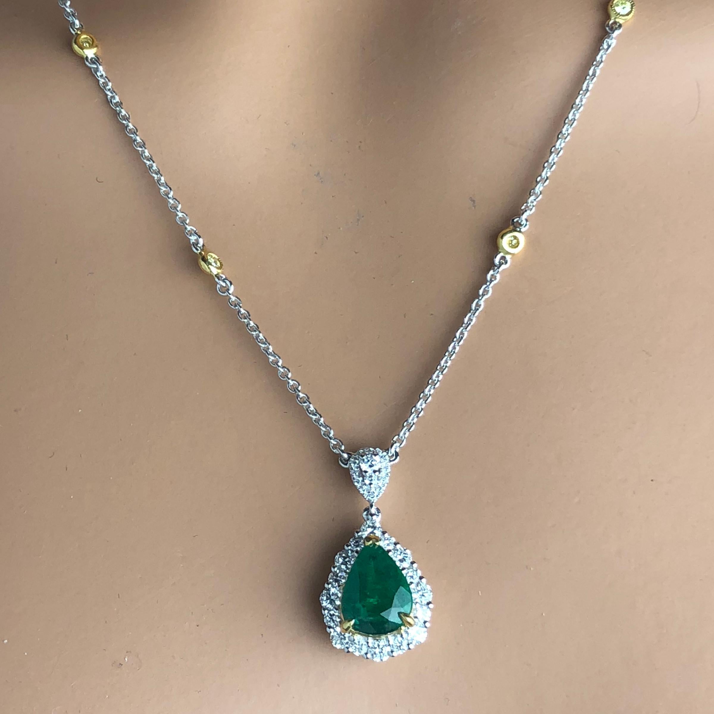 This gorgeous pendant features a 2.10 carat pear shaped Emerald center, surrounded by a halo of round white diamonds. The decorated bail also features white diamonds. With diamonds placed along the chain, the total diamond weight is 0.88