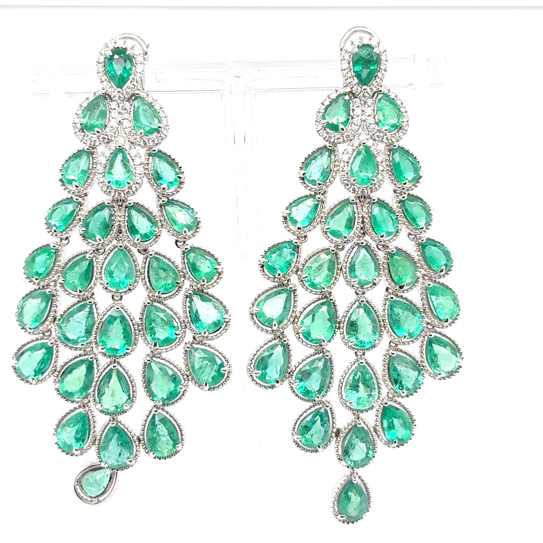 Une paire de boucles d'oreilles chandelier captivante avec 21,02 carats d'émeraudes taillées en poire. Les quatre émeraudes supérieures sont gracieusement encadrées par des halos de 0,19 carats de diamants blancs étincelants, rehaussant leur allure