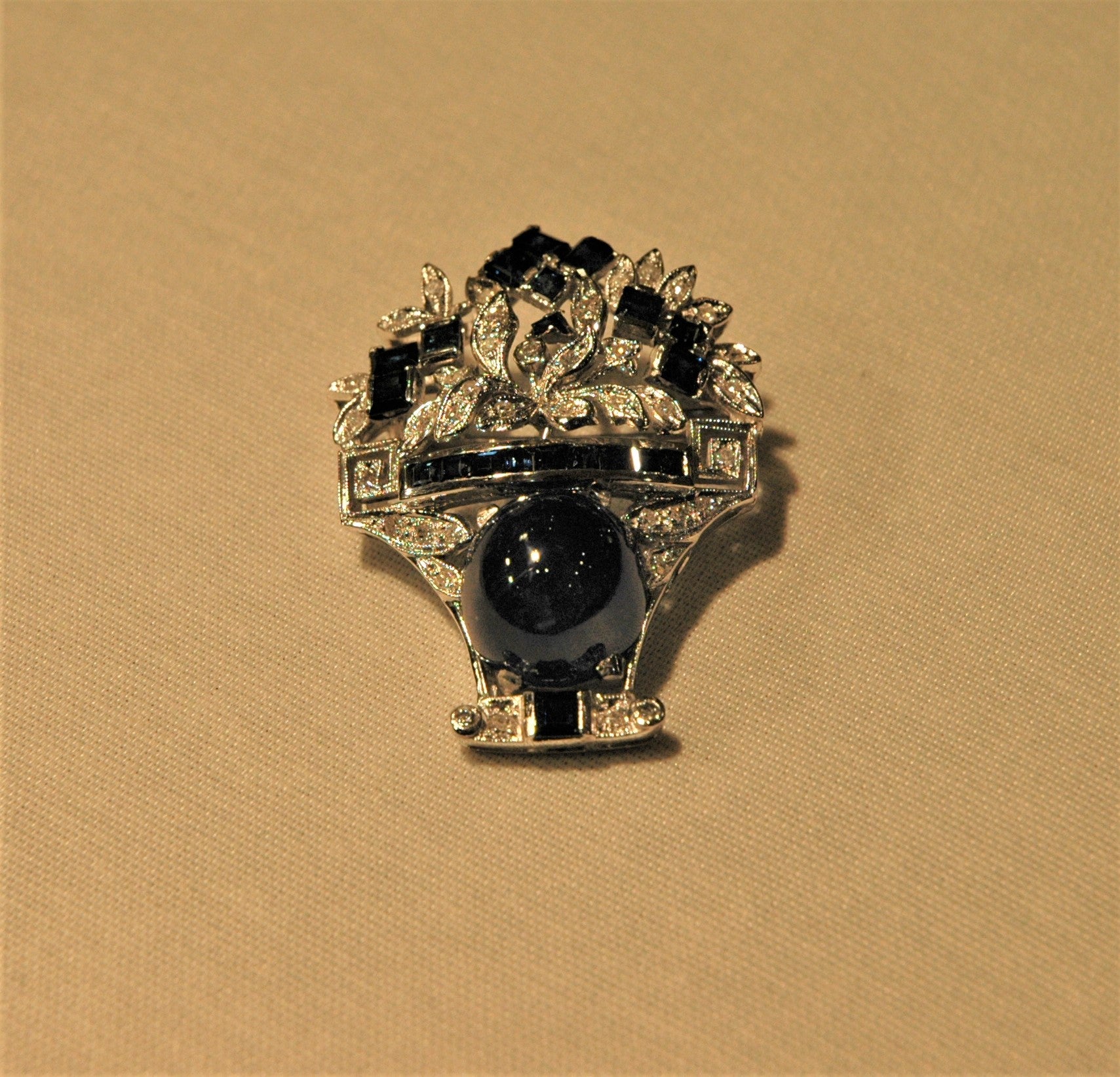 Beautiful basket brooch handmade in Italy with white gold, a central cabochon sapphire, diamonds and baguette-cut sapphires. The brooch may be used also as a pendant, letting a thin chain pass through the holes in the back frame of the brooch.