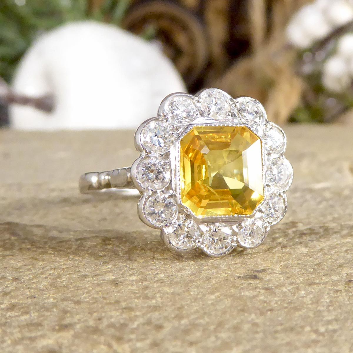 This fabulous Contemporary cluster ring dazzles on the hand with a beautifully coloured Yellow Sapphire featuring in the centre. The Asscher Cut Yellow Sapphire stone weighing 2.10ct is surrounded by a total of 0.90ct bright Brilliant cut Diamonds.