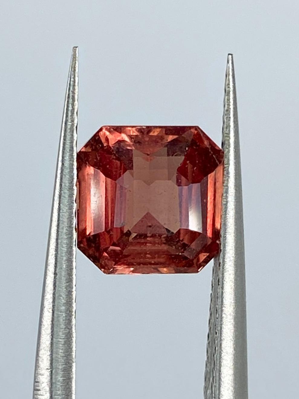 The Sapphire Merchant presents this rare treasure from the heart of Sri Lanka: our Natural Padparadscha Sapphire. Weighing 2.10 carats, this exquisite gem is an embodiment of timeless elegance. Its emerald shape, cut with precision into a step cut,
