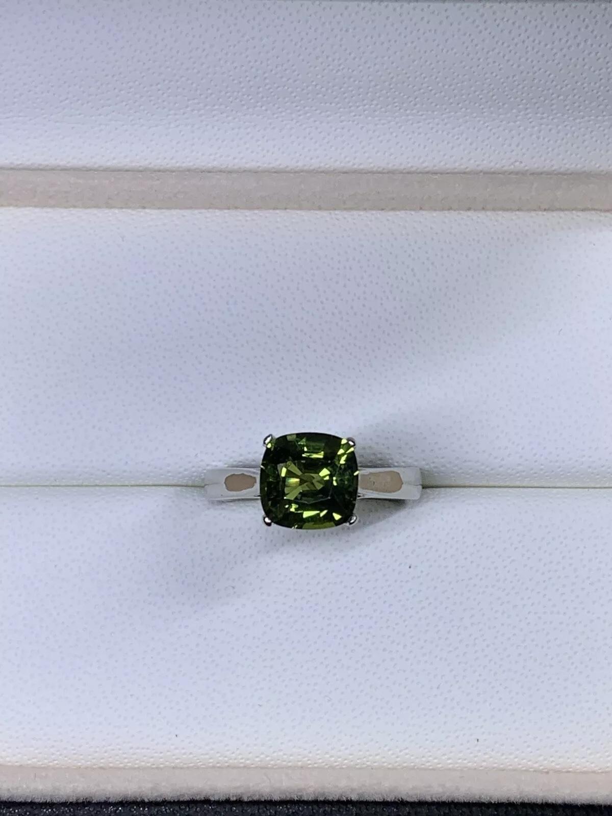 This exquisite 2.10ct green sapphire solitaire ring is the perfect choice for the engagement occasion. Crafted from 18ct white gold, this ring is a stunning piece of fine jewellery that exudes elegance and sophistication. The cushion cut of the