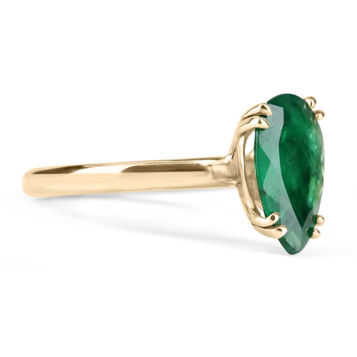 Displayed is a custom emerald solitaire pear-cut engagement/right-hand ring in 14K yellow gold. This gorgeous solitaire ring carries a 2.10-carat emerald in a 4, double prong setting. The emerald has very good clarity with minor flaws that are