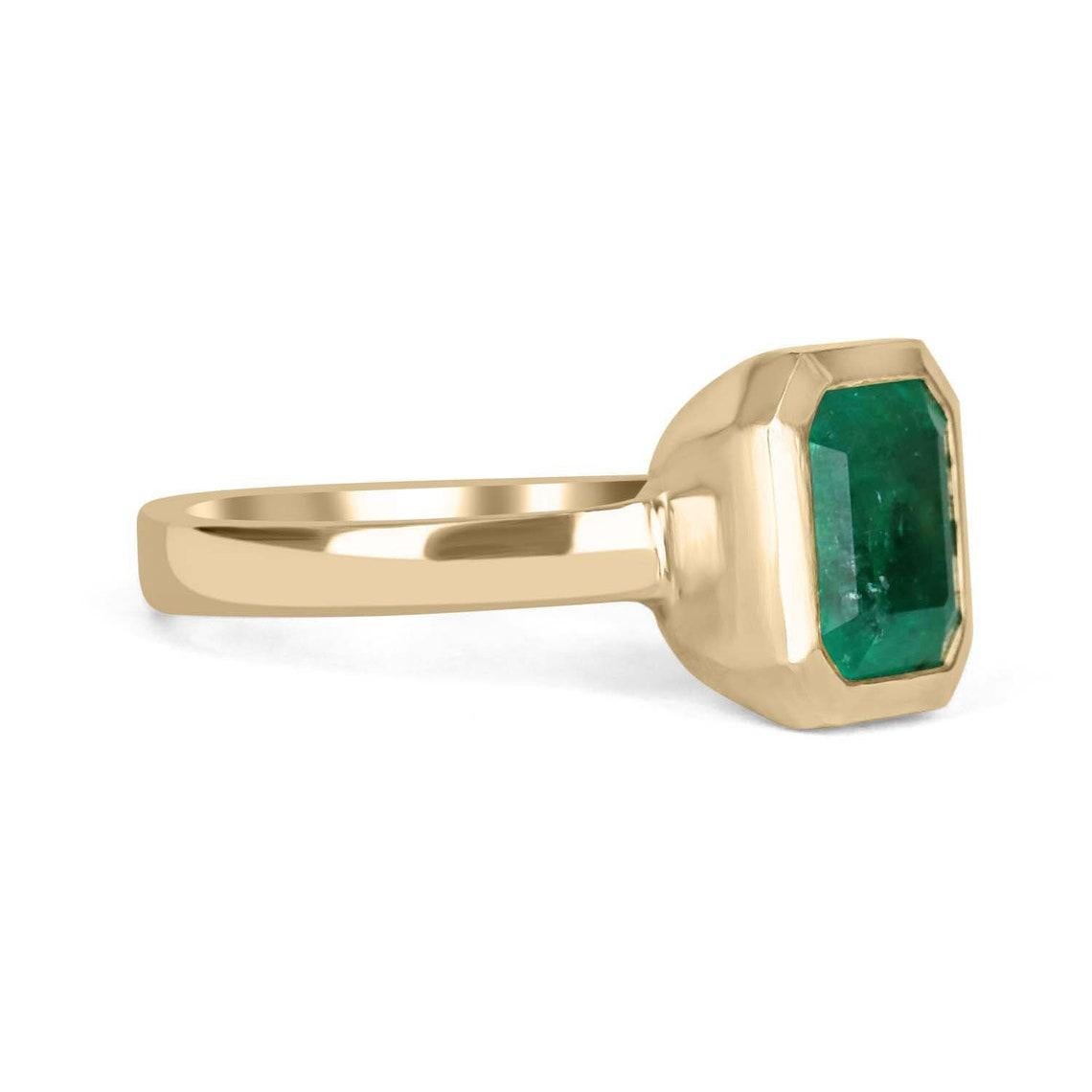 Displayed is a rich medium-dark green genuine Zambian emerald, solitaire, Asscher-cut bezel ring in solid 14K yellow gold. This gorgeous solitaire ring carries a full 2.10-carat EARTH MINED emerald in a sleek and secure bezel setting. The emerald