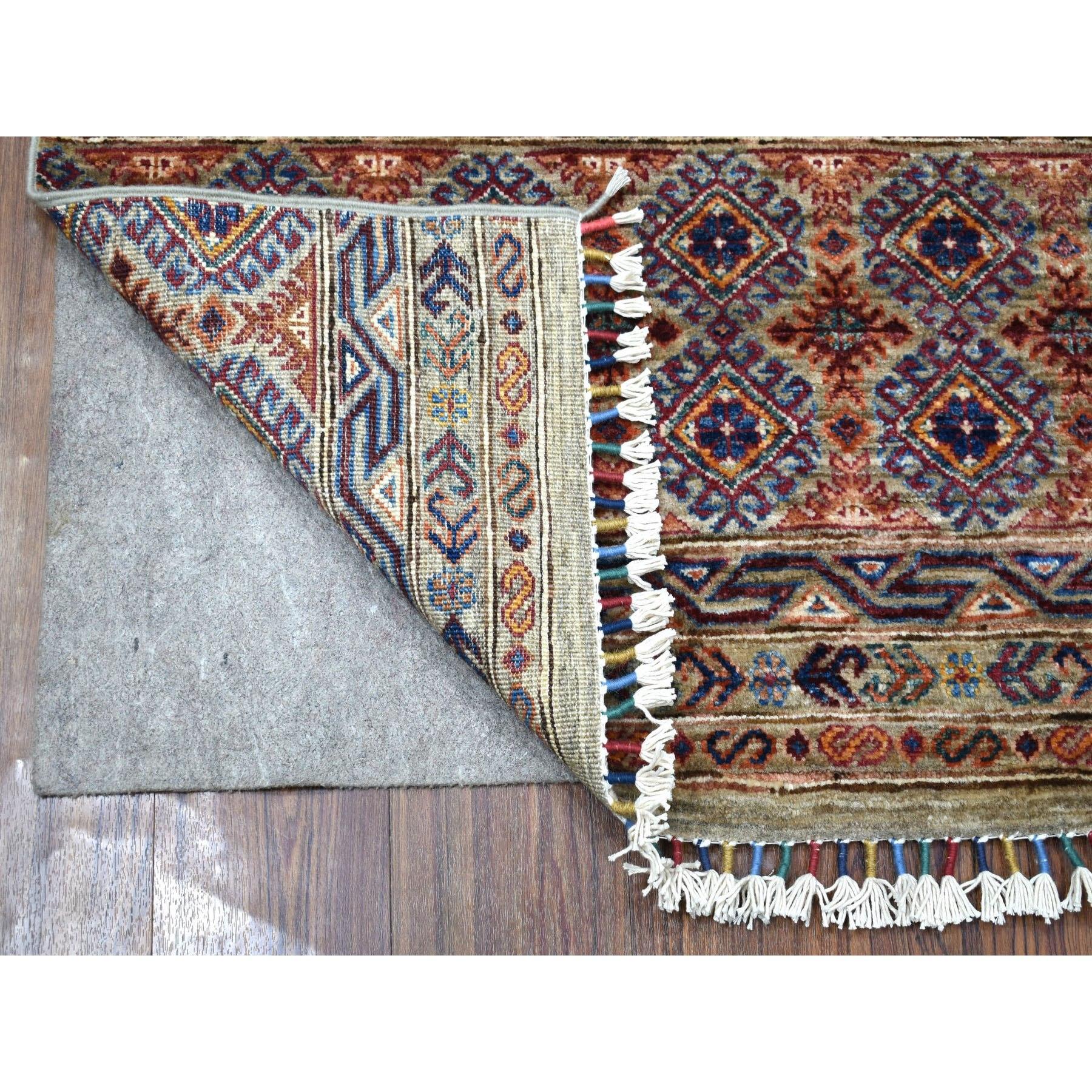 Il s'agit d'un véritable tapis de course oriental en laine pure, noué à la main, de couleur grise, au motif Super Kazak Khorjin avec des glands colorés. Il a été noué pendant des mois et des mois selon des techniques de tissage séculaires par des