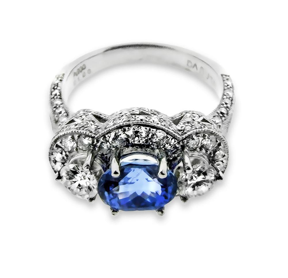 A stunning platinum engagement ring, created by world renowned jewelry designer, Danuta, with a natural non-heated oval cut Ceylon Sapphire (2.11 carats) and one carat in brilliant white side diamonds (F/VS1) and two 30-point side diamonds (F/VS1).