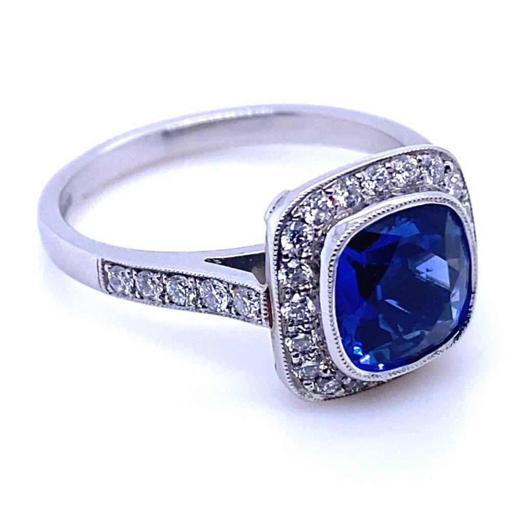 A 2.12 carat sapphire and diamond cluster platinum engagement ring.

This contemporary and classic cluster ring is set with an exceptional royal blue sapphire cushion cut centre and round brilliant cut diamond surrounds leading to further half