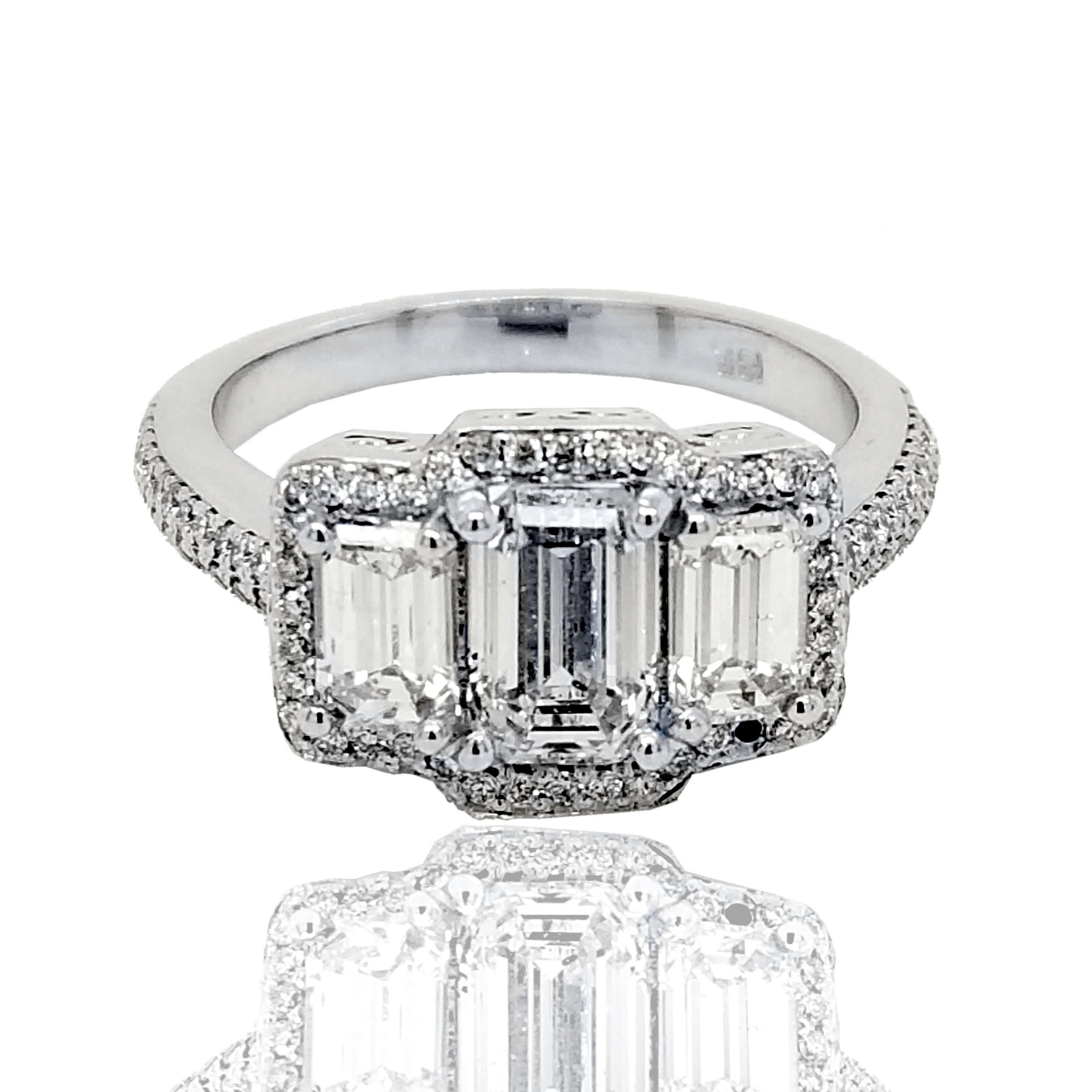 Magnifique diamant central de 1,04 ct de taille émeraude F-G/SI2 serti dans une bague de fiançailles à 3 pierres en or 18 carats avec 2 diamants de taille émeraude.  diamants sur le côté avec le halo et la tige sertis de pavés. Poids total des