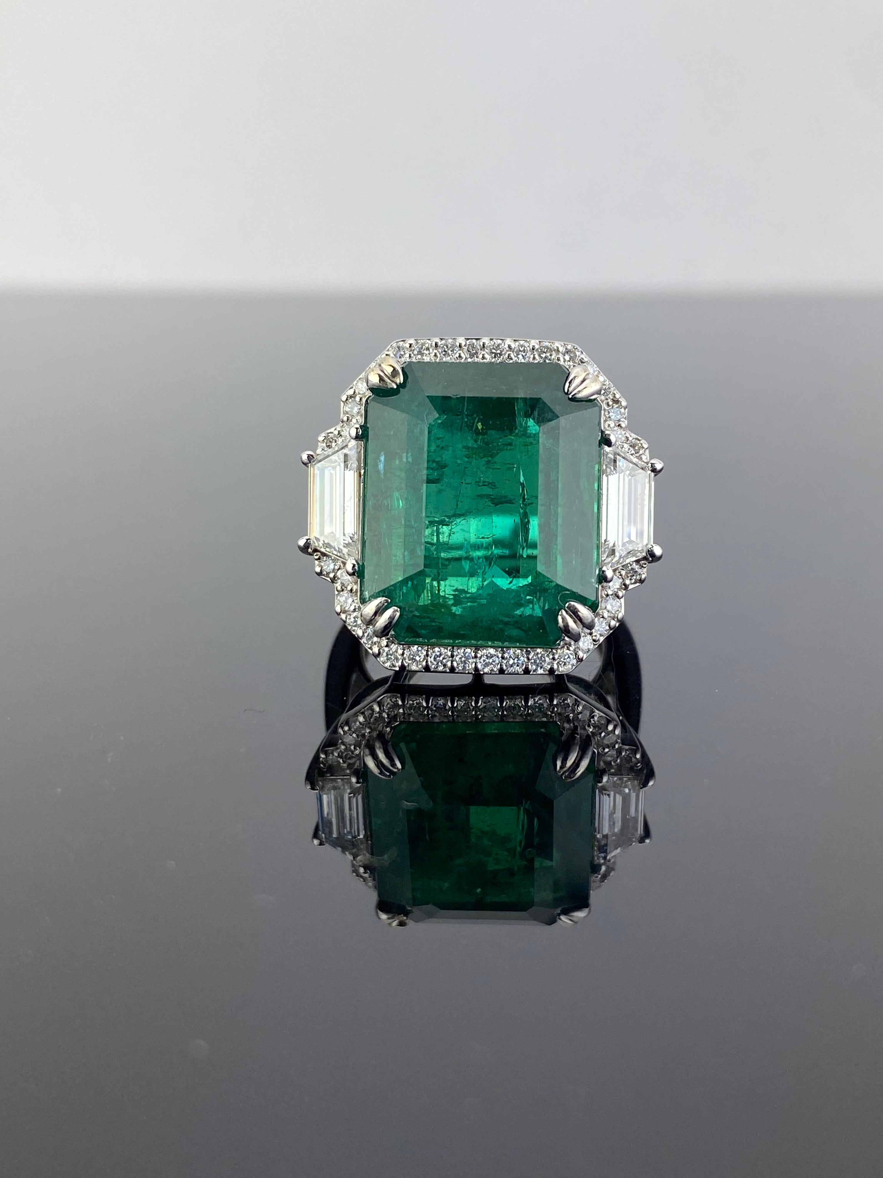 An exceptional natural 21.27 carat Zambian Emerald and 0.94 carat trapeze shaped VS quality White Diamonds three-stone cocktail ring, with a border of 0.46 carat White Diamonds. The centre stone, is definitely one of a kind, collectors item -
