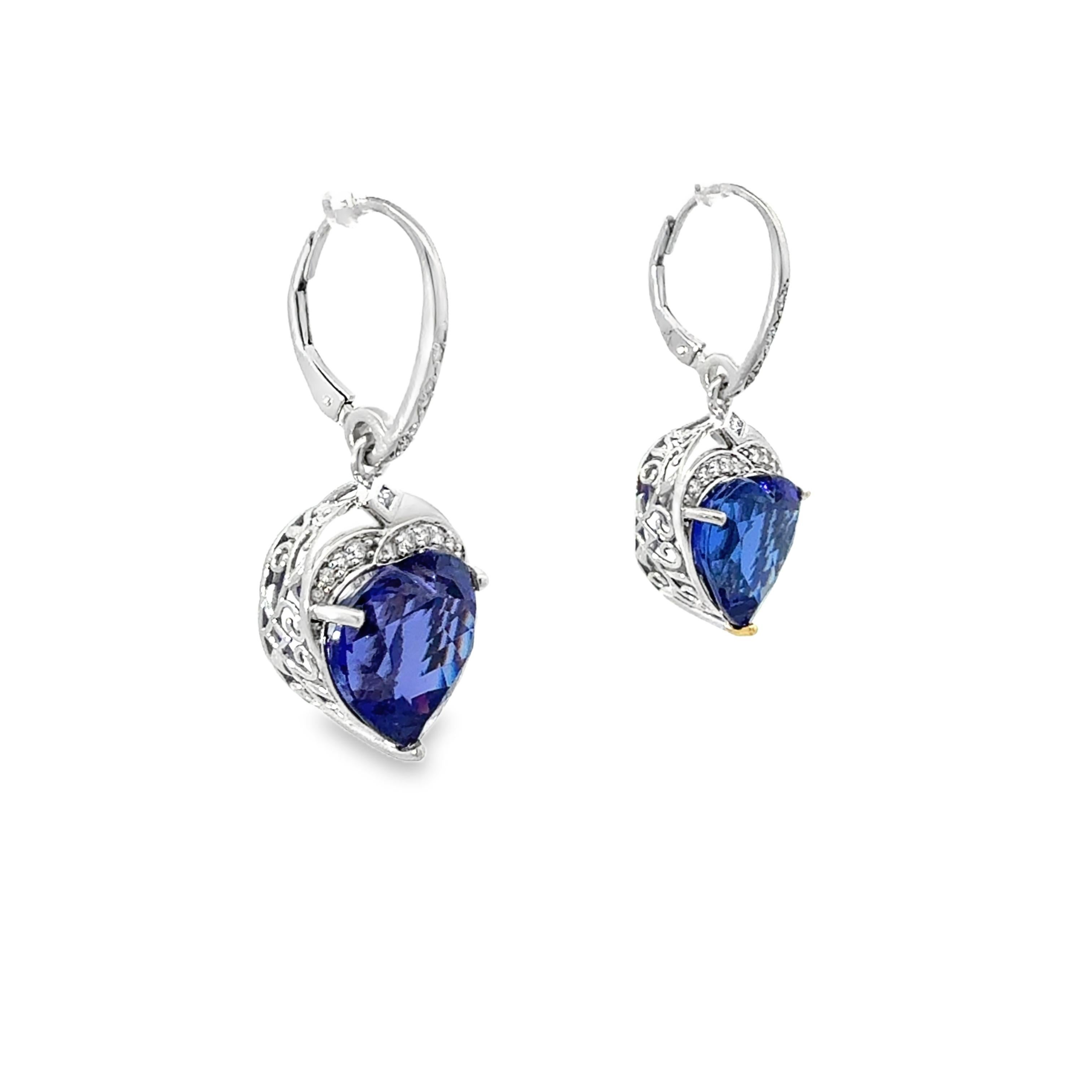 These stunning heart-shaped tanzanite and diamond dangle earrings are a bold statement of elegance and charm. Crafted in luxurious 18-karat white gold, they feature two vibrant heart-shaped tanzanites totaling 21.28 carats, each displaying lively