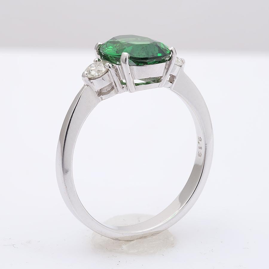 This oval cut Tsavorite Garnet, set at the center of this ring steals the show. It’s rich green, has been highlighted by the perfectly matched round brilliant diamonds that rest on either side of the center stone. Eye clean and large in size, this