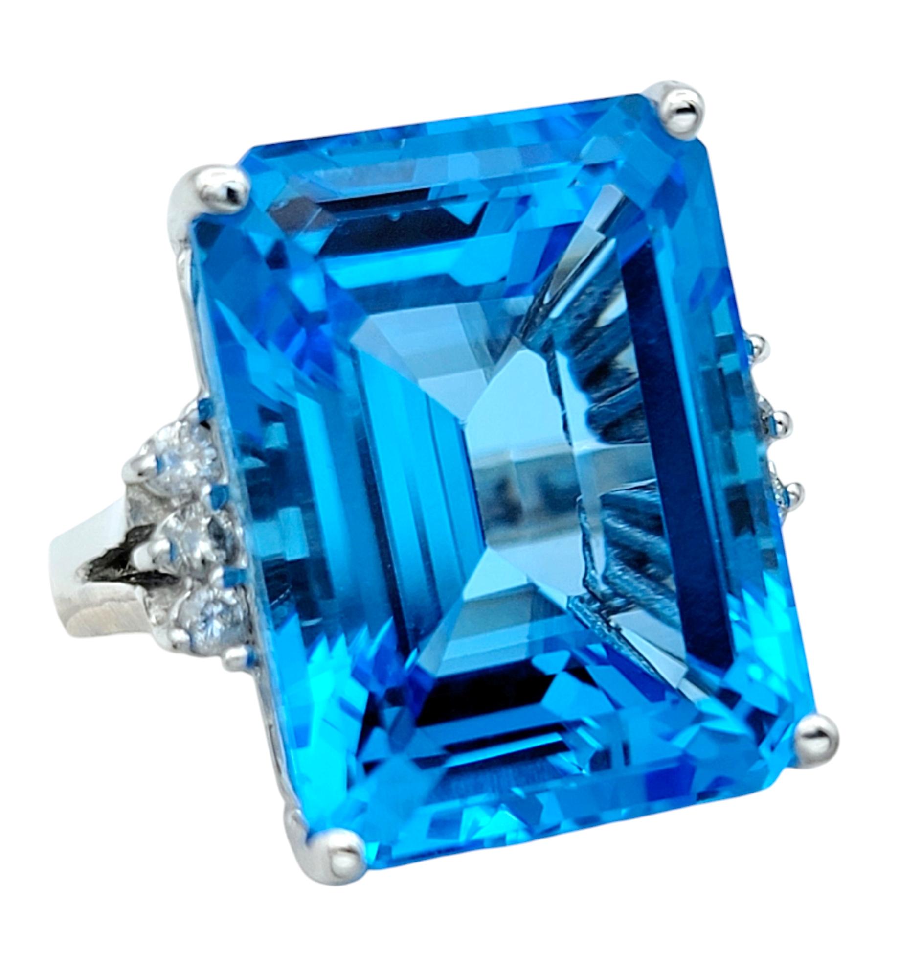 Ring Size: 6

This striking ring showcases a magnificent 21.39 carat emerald cut blue topaz, capturing attention with its deep, vibrant blue hue. The sharp lines of the emerald cut beautifully highlight the topaz's clarity and natural brilliance,