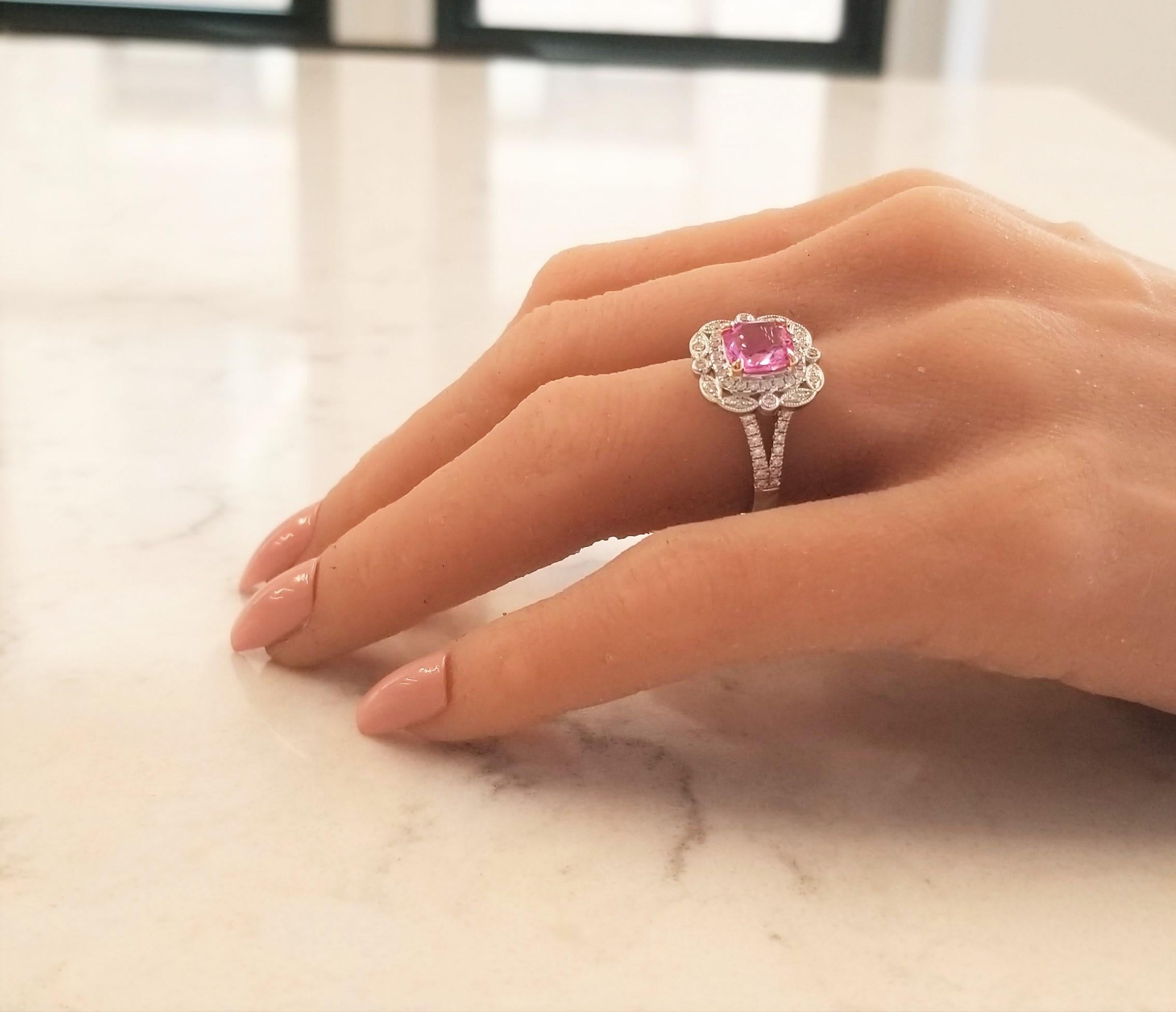 This lovely ring features a 2.14 carat cushion cut pink sapphire. This gem source is Sri Lanka. It measures 7.45 x 7.00 mm; its transparency and clarity is excellent. It is vibrant pink, bubble gum pink; it is framed with a complex border of 0.45