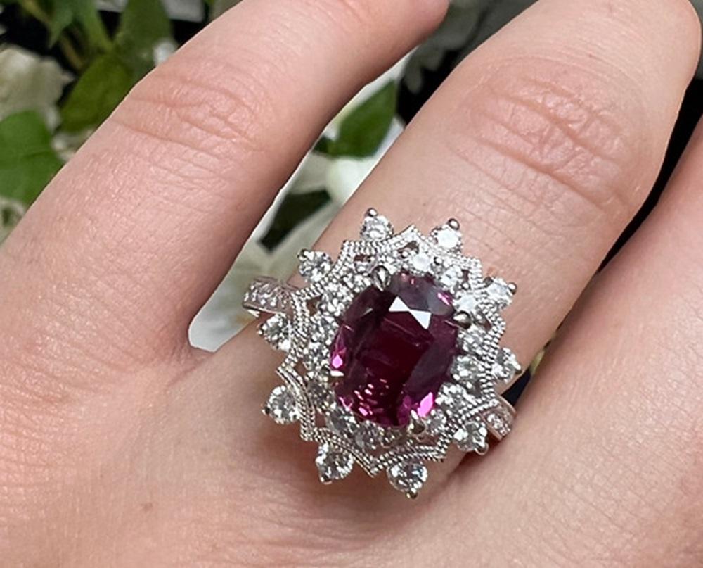 Ruby Weight: 2.14 CTS, Ruby Measurements: 9.04 x 6.79 mm, Diamond Weight: 0.96 CT, Metal: 18K White Gold, Ring Size: 6.5, Shape: Oval, Color: Purple-Red, Hardness: 9, Birthstone: July