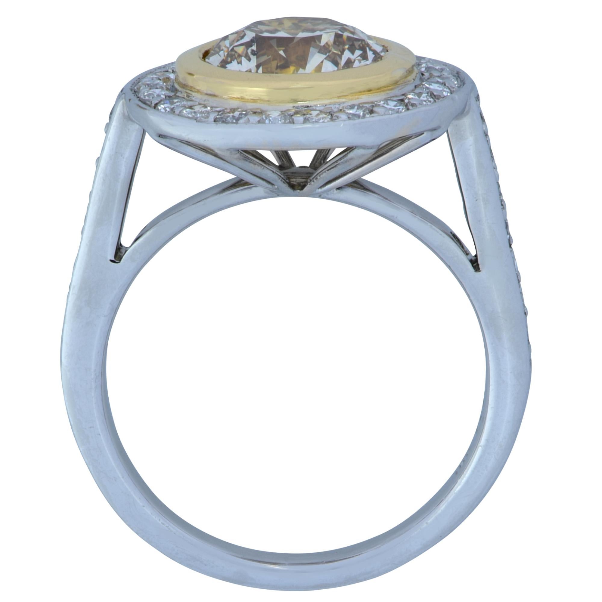 Stunning ring crafted in platinum and 18 karat yellow gold, featuring a cognac color round brilliant cut diamond weighing approximately 2.15 carats, surrounded by 35 round brilliant cut diamonds G-H color, VS Clarity. The center diamond is set in an