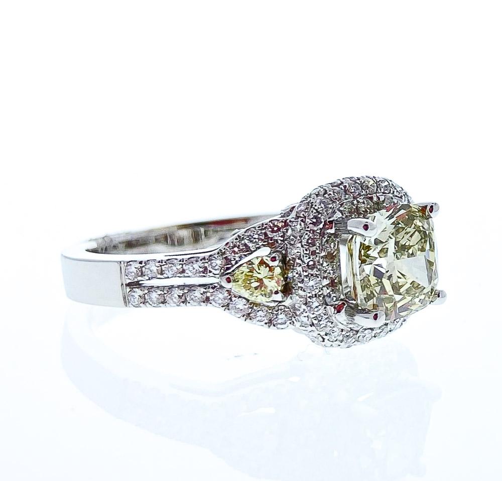 This show-stopping brightly polished 18 karat white gold engagement ring features a total of 2.15 carats of fancy yellow cushion cut and side stone diamonds, prong set in a stunning 3-stone anniversary style. A total of 1.06 carats of melee round