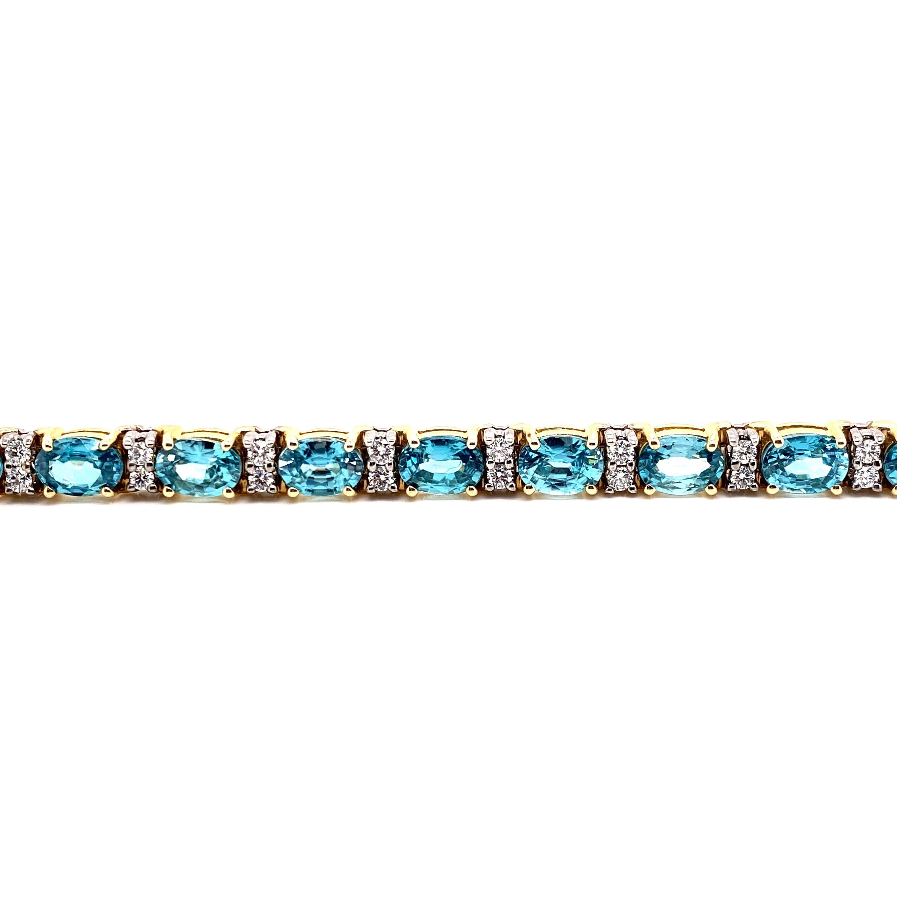 Questo splendido bracciale di zirconi blu e diamanti presenta 18 splendidi zirconi blu ovali, ognuno dei quali è separato da una serie di 2 radiosi diamanti bianchi rotondi. Questo bracciale è incastonato in oro giallo e bianco 14K, con cestini in