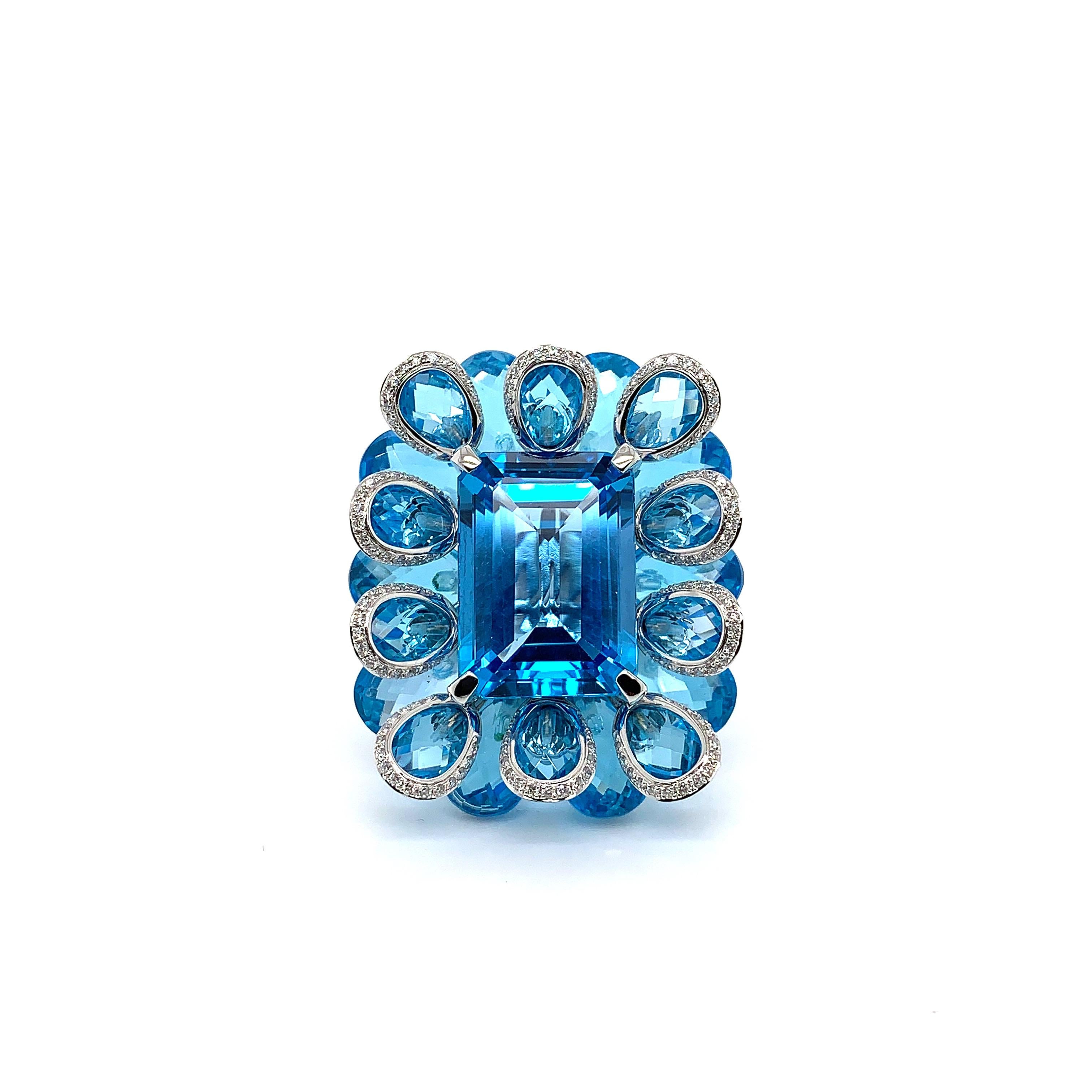 This ring features an exquisite 21.51 carat blue topaz as the center stone. This gorgeous gemstone is laid on top of a bed of luscious blue topaz briolettes to highlight the peaceful hue of the gems. The architectural layering of the floral blue