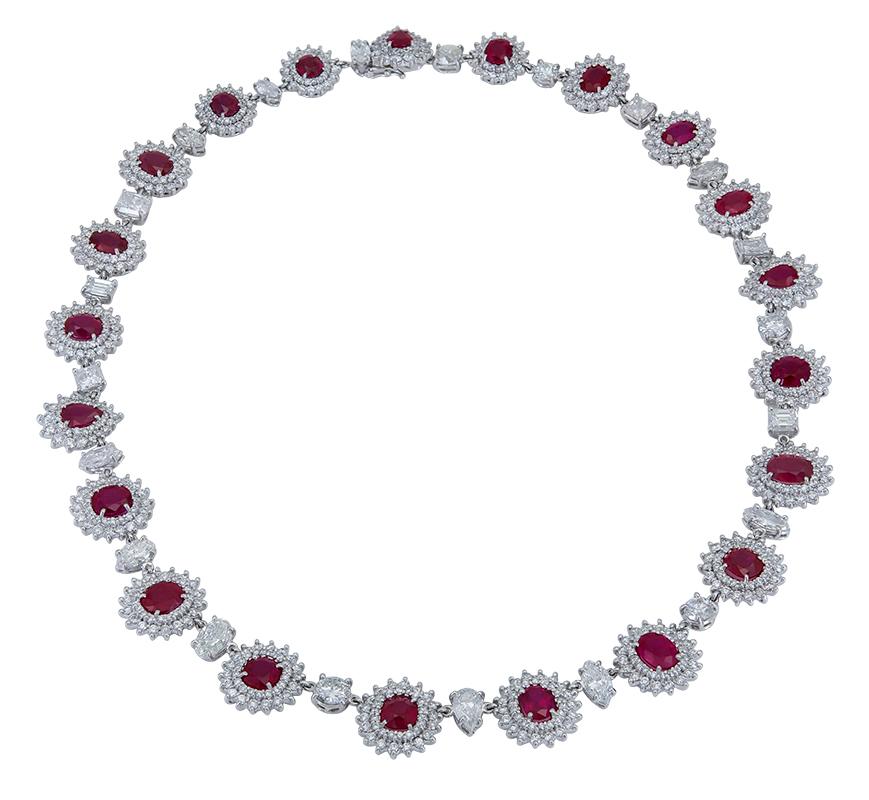Un collar de estilo chic que sin duda elevará tu atuendo. Presenta una hilera de vibrantes rubíes rojos rodeados de brillantes diamantes redondos engastados en un motivo floral. Cada halo de rubí y diamante está espaciado por un único diamante de