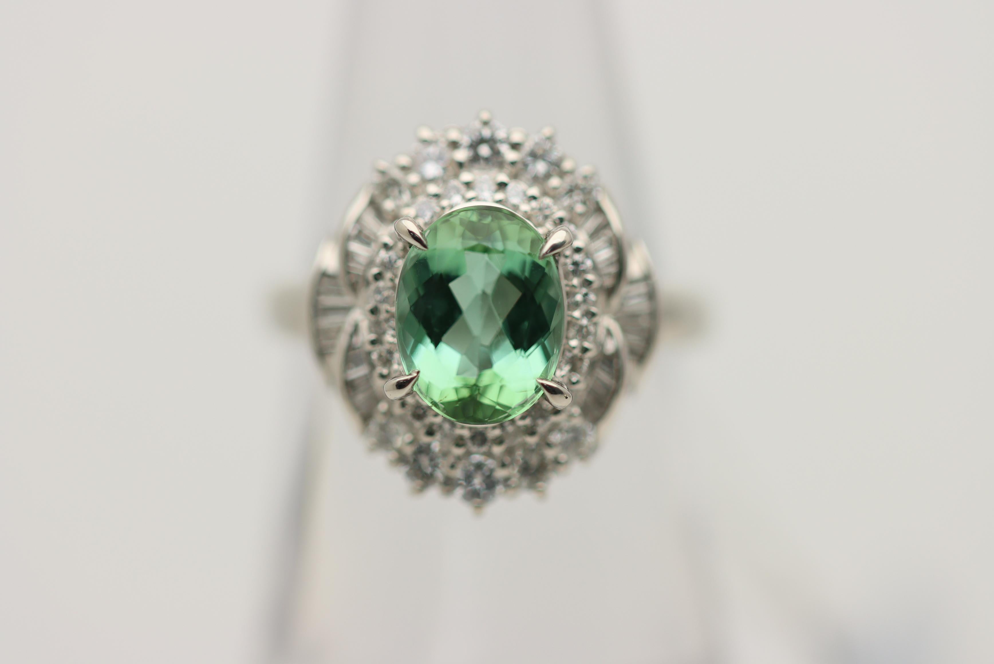 A stylish platinum ring featuring a fine gem mint tourmaline. It weighs a respectable 2.16 carats and has an intense alpine mint green color with excellent brightness and light return. It is complemented by 0.64 carats of round brilliant and