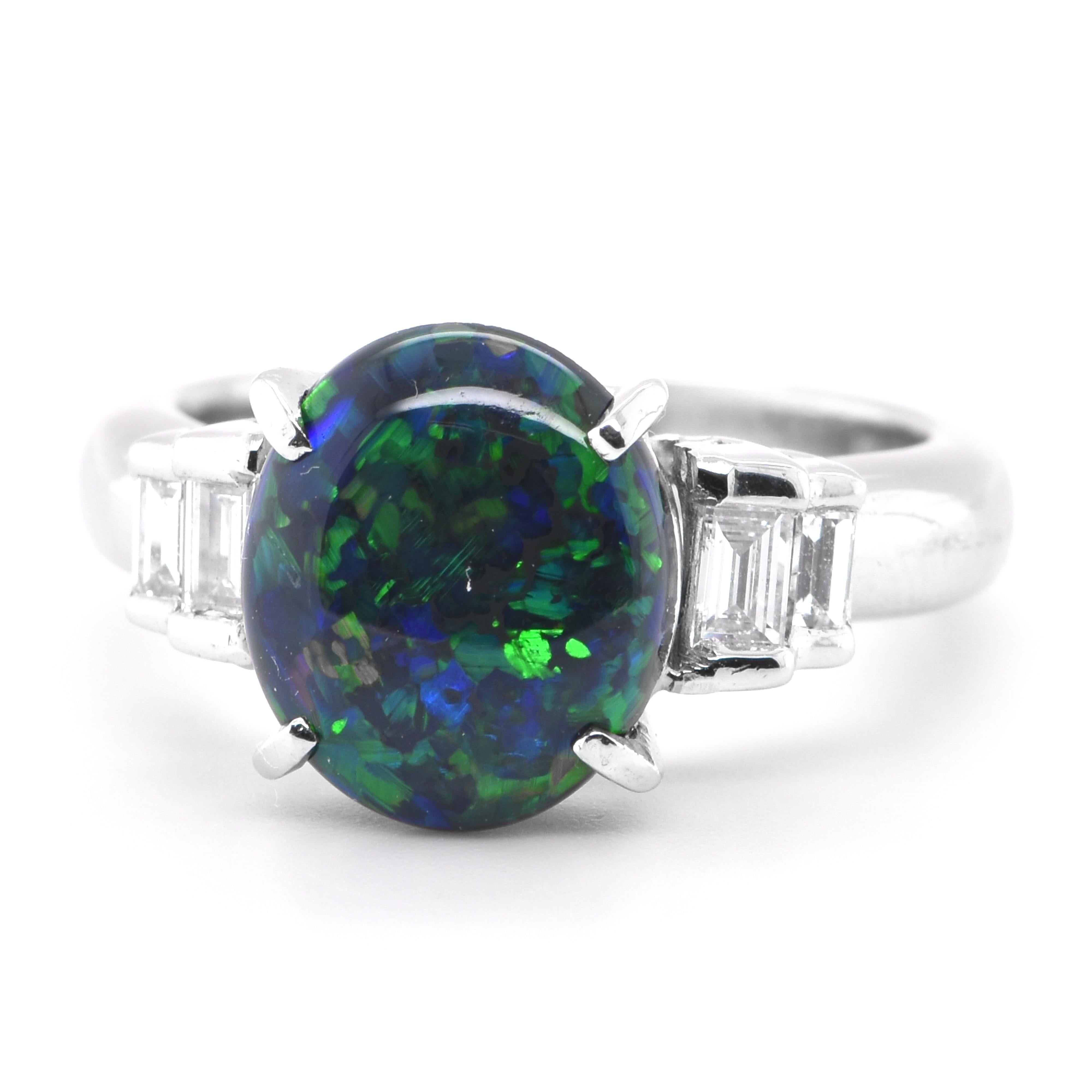 A beautiful three-stone ring featuring a 2.16 Carat, Natural, Australian Black Opal and 0.25 Carats of Diamond Accents set in Platinum. The Opal displays very good play of color! Opals are known for exhibiting flashes of rainbow colors known as