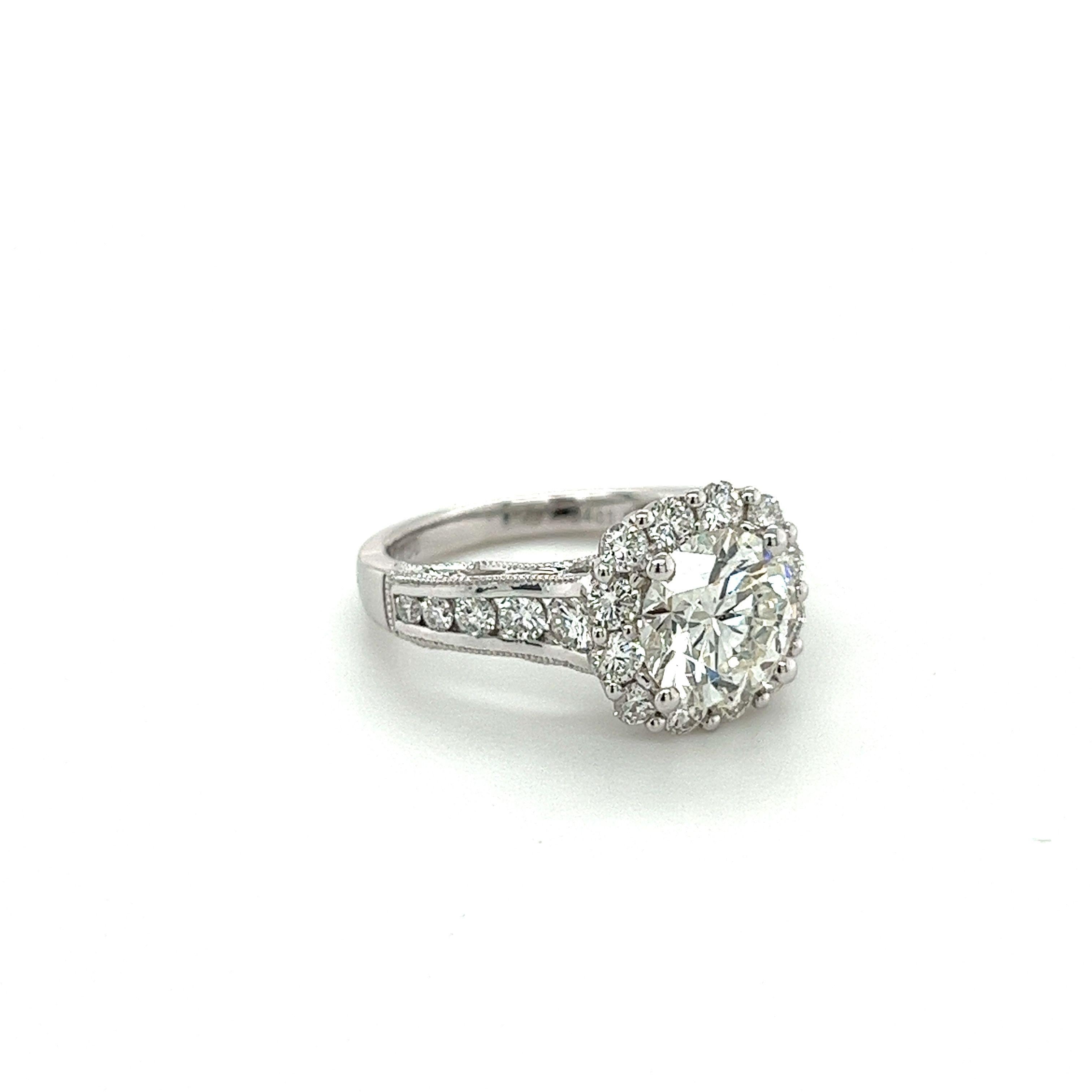 Introducing a natural, mined diamond engagement ring that is anything but traditional. Featuring a unique filigree-designed setting with a curved floral motif shank. This ring displays a gorgeous white diamond halo and notably sized graduating