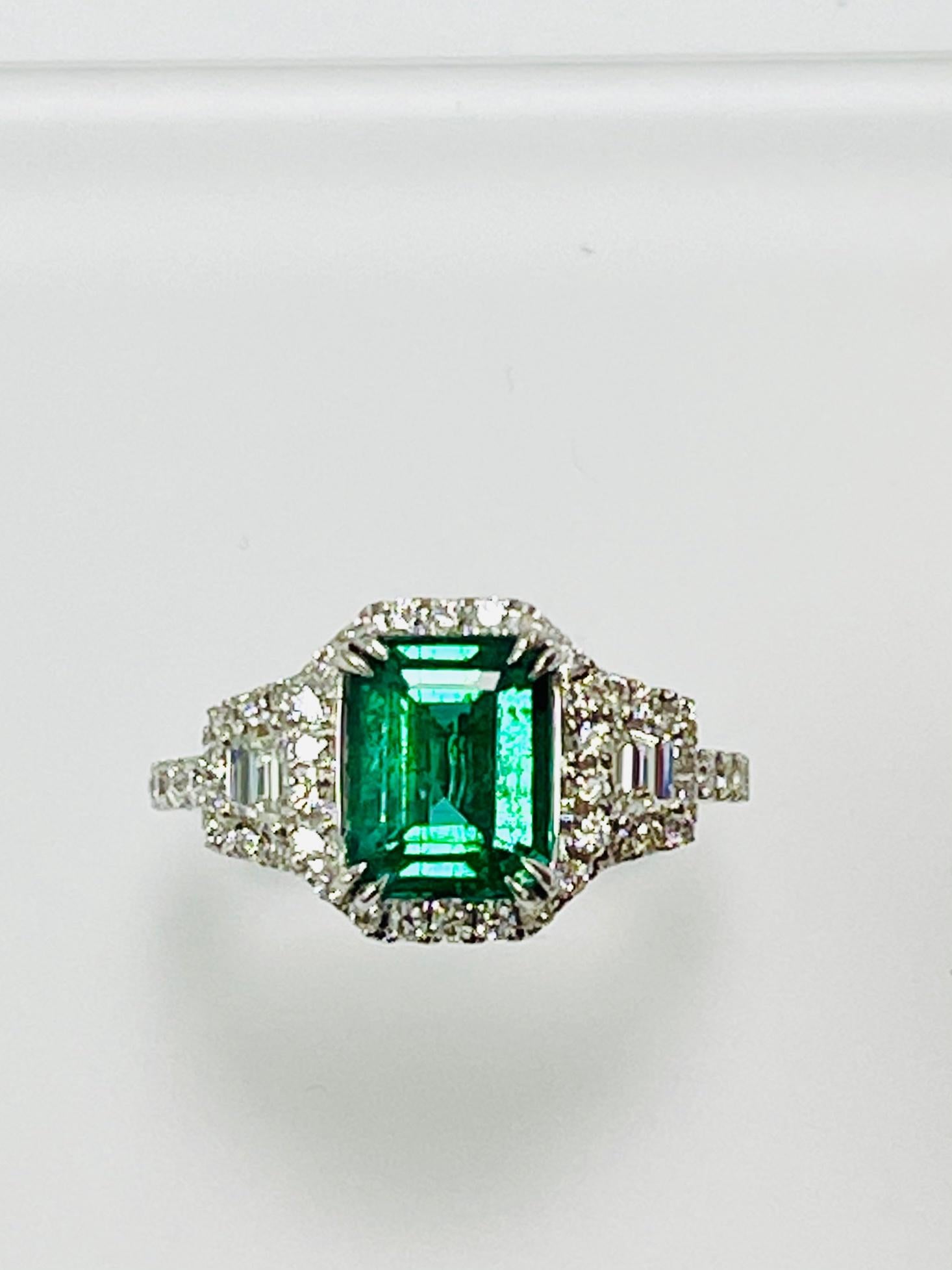 2.16 Carat Emerald cut Zambian emerald set in 18k white gold ring with 0.88 ct round diamonds around it and half way on the shank, with trapezoid diamonds .
