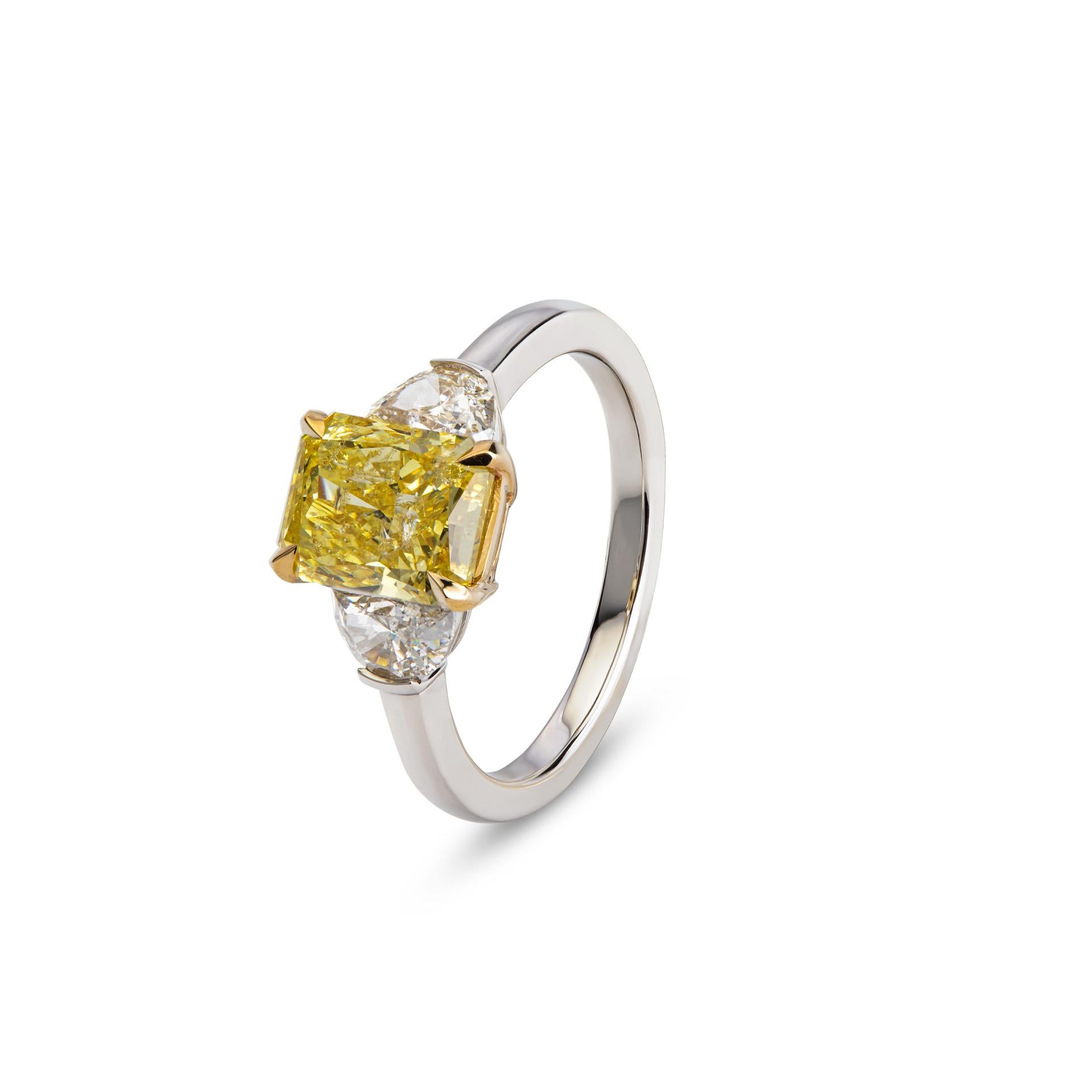 At its heart lies a captivating 2.16-carat radiant fancy intense yellow diamond, certified by GIA. The central stone, with its vibrant hue commands attention and radiates elegance. Flanking the central Diamond are two exquisite half-moon diamonds,