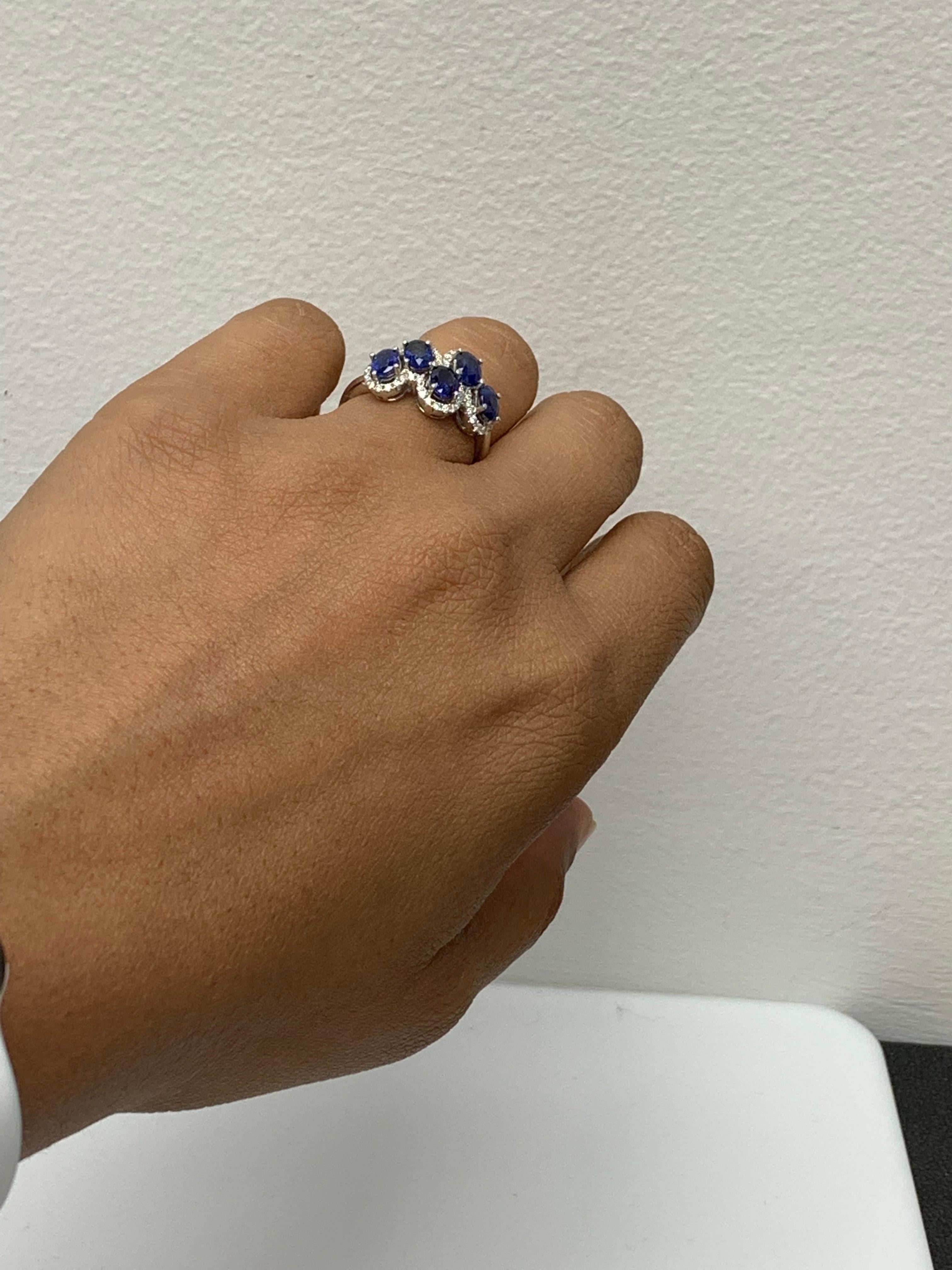 Beautiful ring set with 5 oval cut blue sapphires weighing 2.17 carats total. Asymmetrically set rubies are surrounded by a single row of round-cut melee diamonds weighing 0.31 carats in total. Set in 18k white gold. 

Size 6.5 US (Sizable). One of