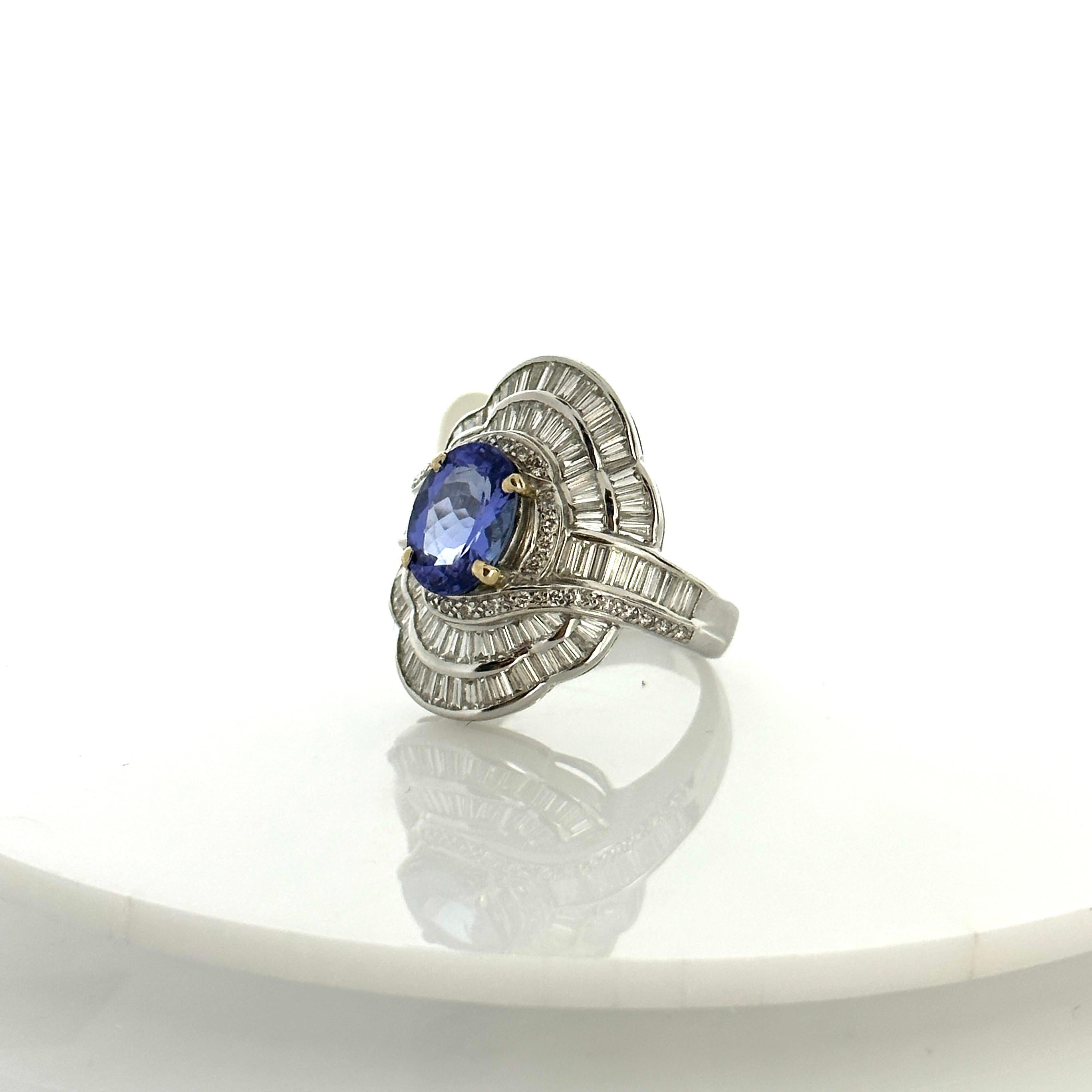 This dazzling ring features a gorgeous 2.17 carats tanzanite center. The gemstone is illuminating and and from the foothills of Mt. Kilimanjaro in Tanzania. The color is a vivid violet-blue. The center is accented by sparkling . 3.56 carats total