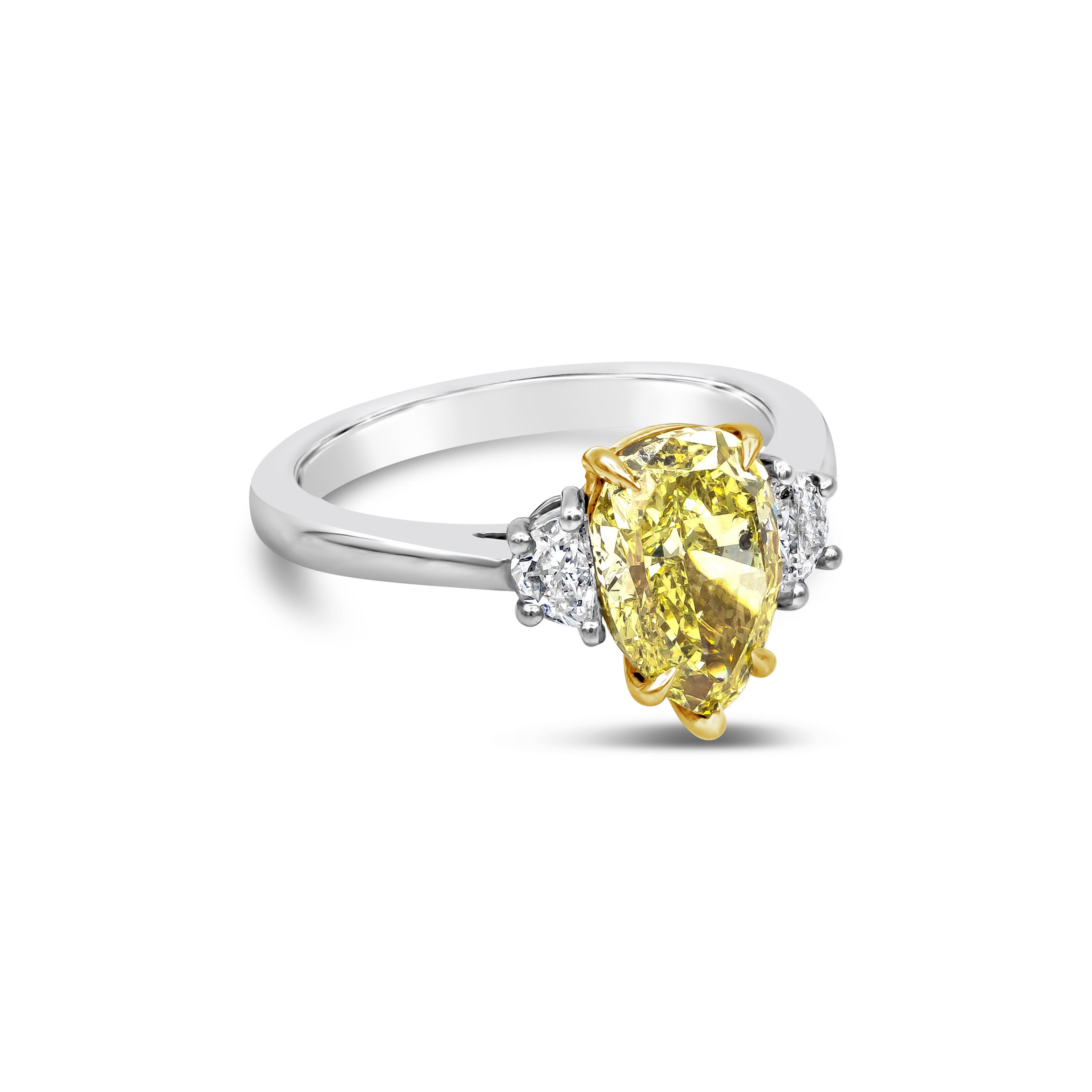 This elegant and stunning three stone engagement ring showcasing a 2.18 carats pear shape diamond center stone certified by GIA as fancy intense yellow color, set in a yellow gold five prong basket setting. Flanking the center are two half moon