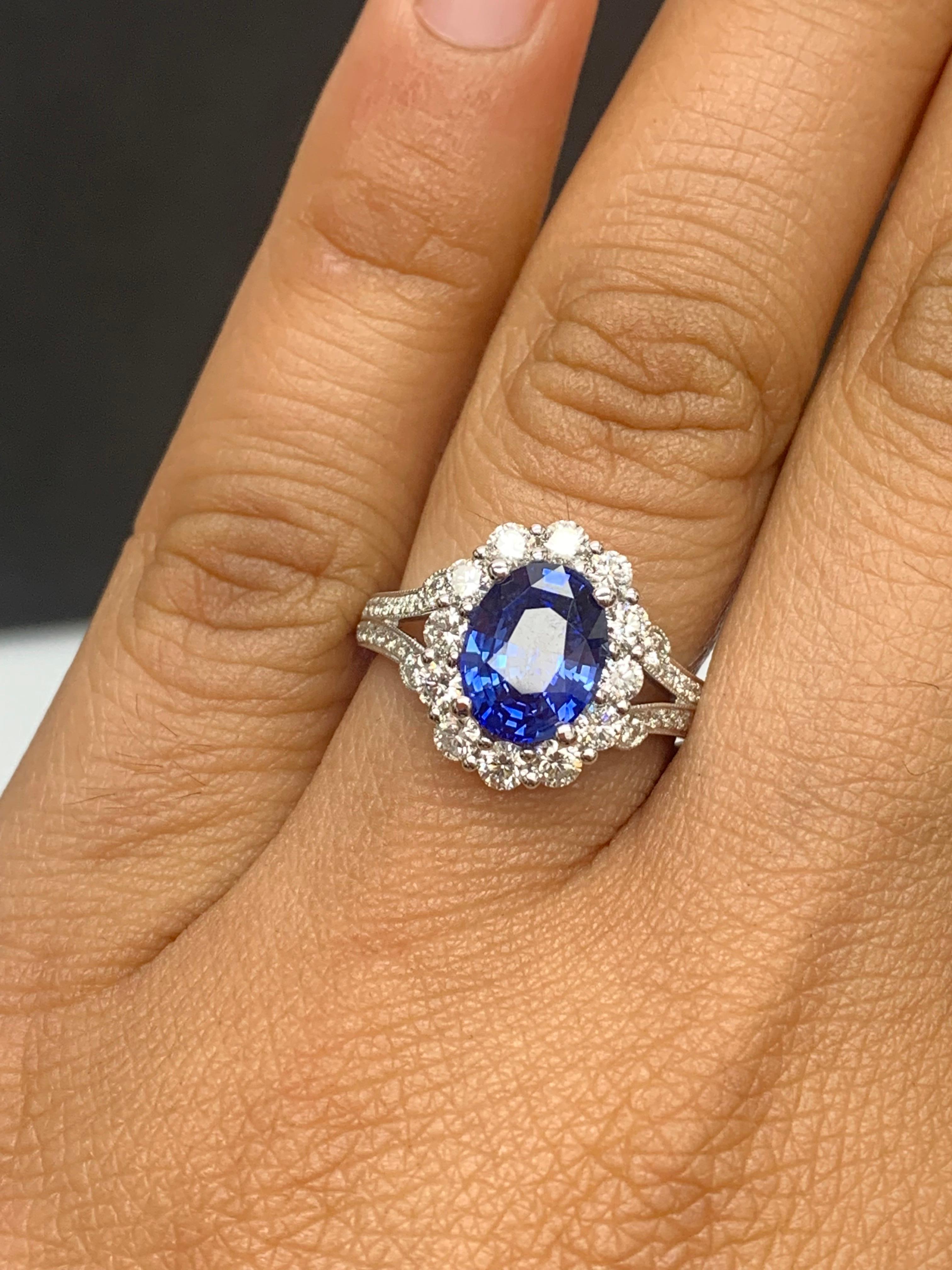 Features a gorgeous flower design  2.18 carat oval cut blue sapphire ring surrounded by a row of brilliant-cut 12 diamonds weighing 0.67 carats in total. 36 accent diamonds on the side weigh 0.28 carats. Made in 18k white gold.