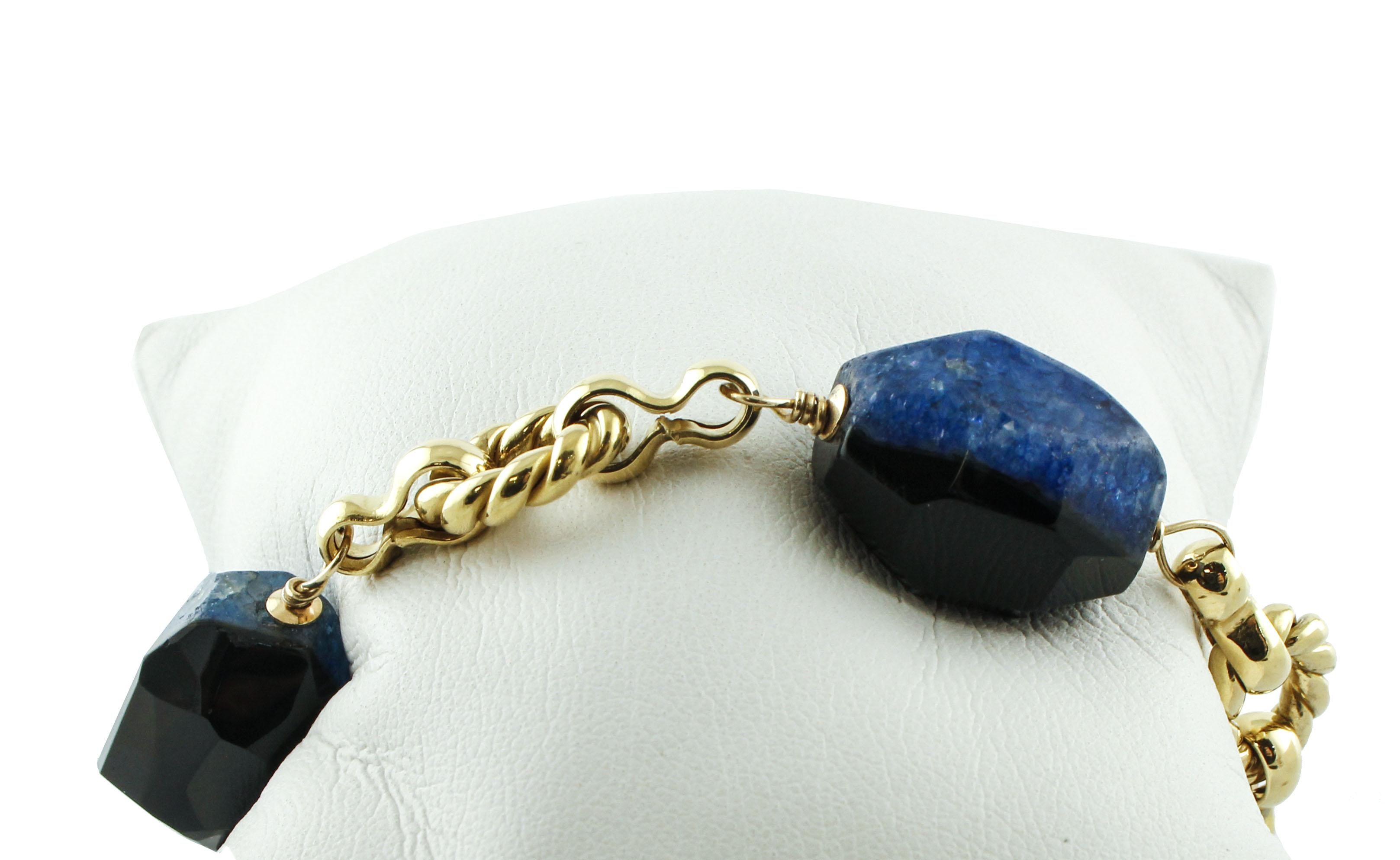 Superbe bracelet Retrò Link en or jaune 18K monté avec 3 pierres de 21.80 g d'agate striée bleue et noire et orné de 0.98 ct de rubis. 
Rubis 0,98 ct 
Agate striée bleue et noire 21,80 g   Diamètre : 17/18 mm  Longueur 20/21 mm 
Poids total 40,60