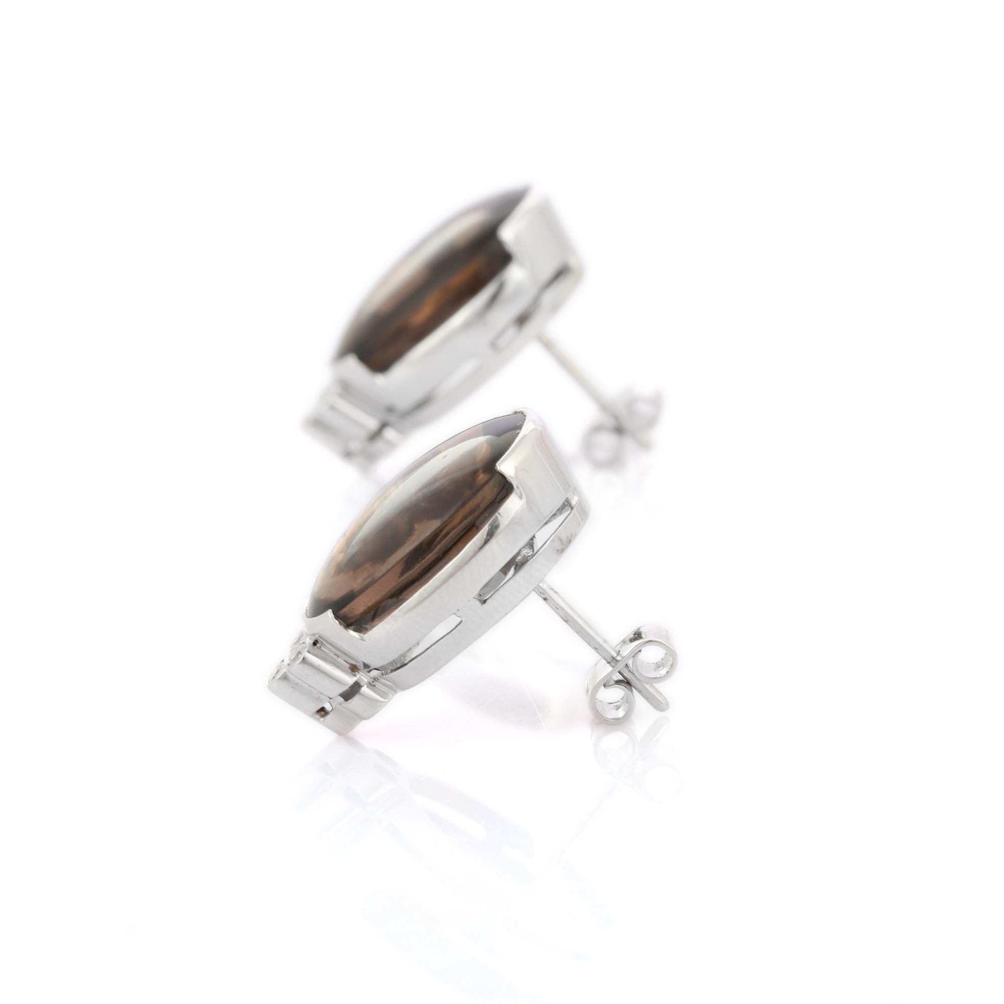 Studs create a subtle beauty while showcasing the colors of the natural precious gemstones and illuminating diamonds making a statement.
Statement oval cut dark brown smoky quartz and diamonds studs in 14K gold. Embrace your look with these stunning
