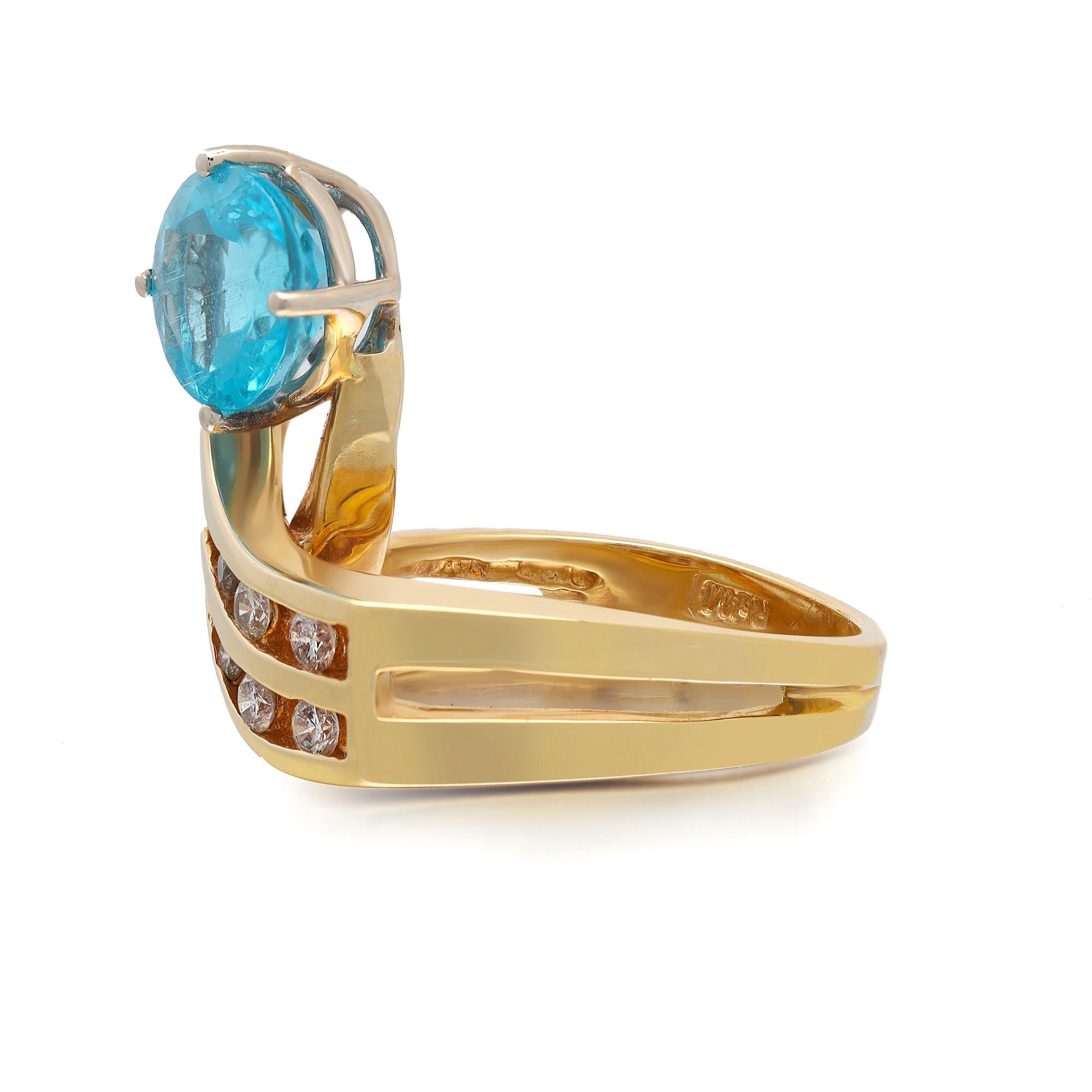 This stunning ring is crafted in 14k yellow gold and features a prong set round cut blue Apatite stone weighing 2.19 carats flanked with round brilliant cut diamonds weighing approx. 0.45 carat. Ring size: 6.5. Total weight: 7.42 grams. Great