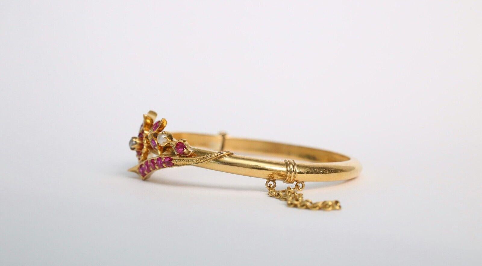 Ce bracelet exquis en or 21 carats présente un motif floral romantique avec des pierres roses vibrantes et de petites perles de rocaille. Conçues dans un style classique, les deux branches du bracelet se courbent élégamment sur le poignet, chaque