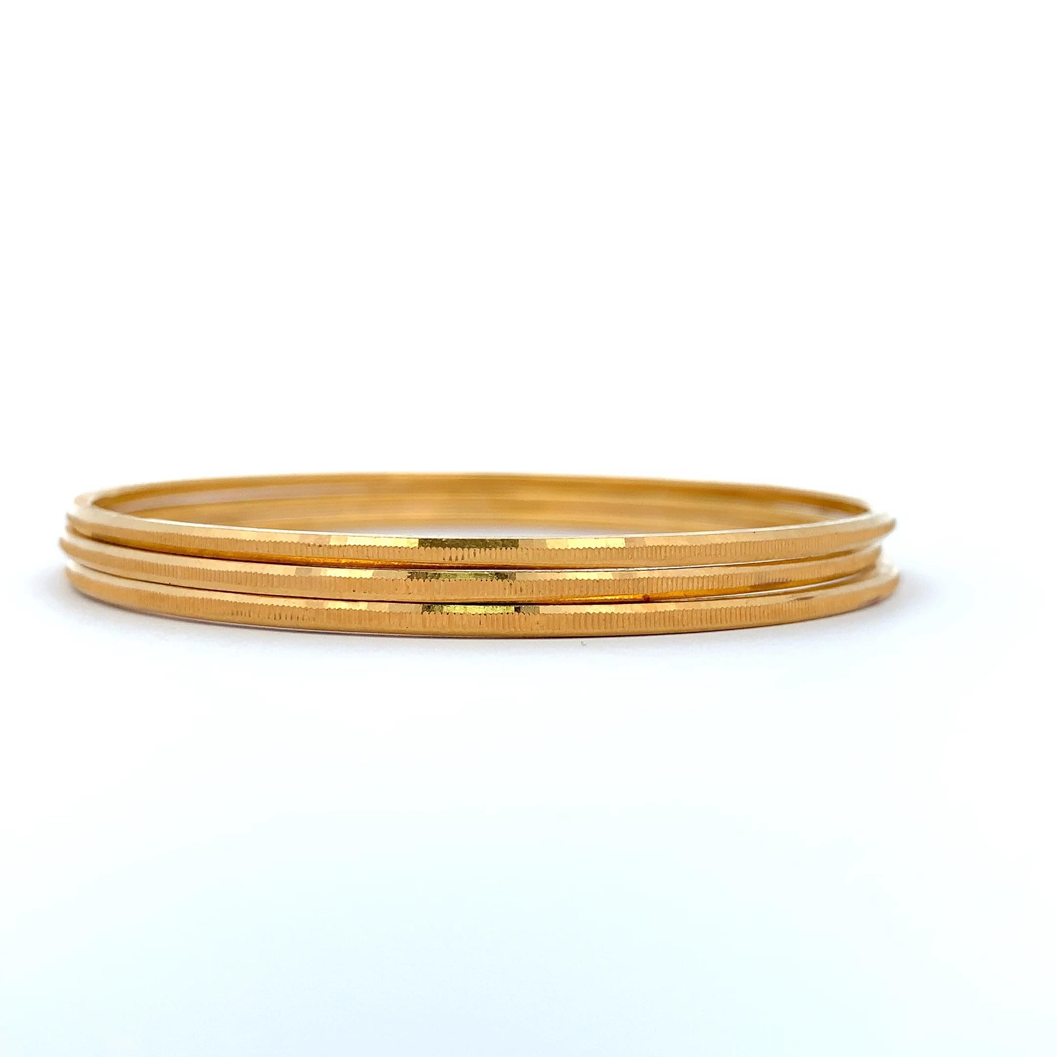 Elevate your style with this radiant 21k yellow gold bangle. Its sleek and polished finish catches the light, creating a mesmerizing glow. Perfect for adding a touch of sophistication to any ensemble, this timeless piece is a must-have for your