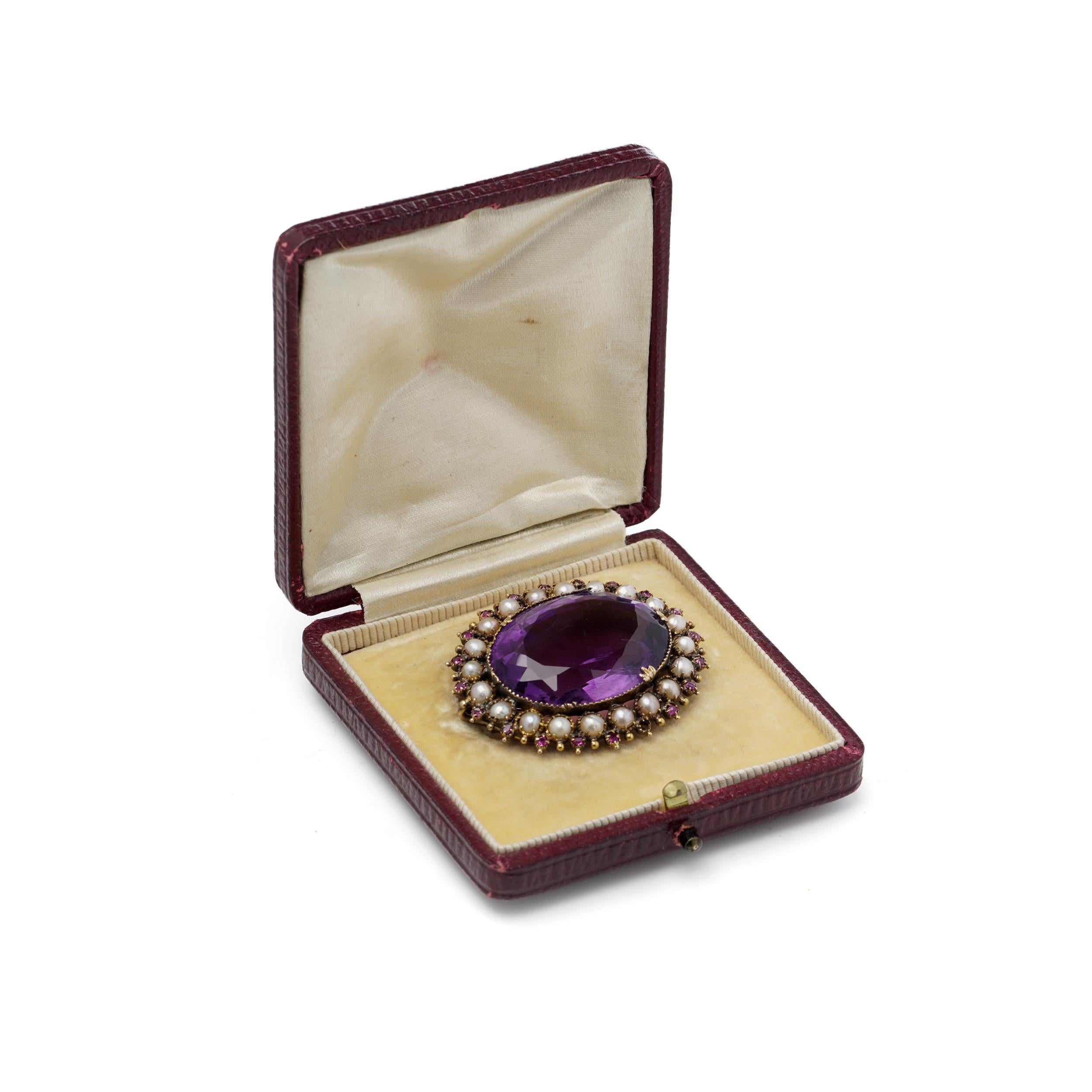 Broche en or jaune 21kt, centrée sur une grande améthyste facettée entourée de perles de rocaille naturelles et de rubis vifs. 
L'améthyste centrale, qui mesure environ 22 x 20 x 16 mm, est estimée à environ 65 carats. 
L'améthyste est encadrée de