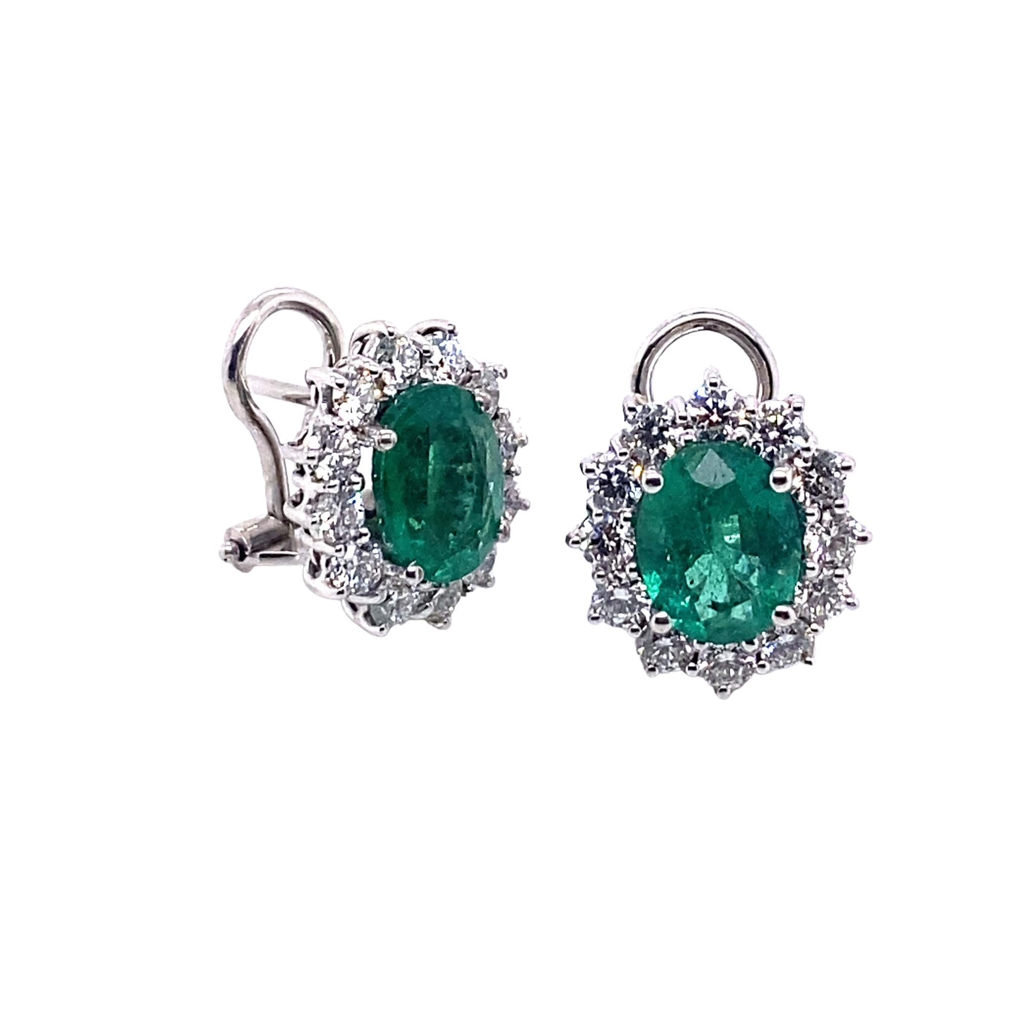 A vibrant pair of emerald and diamond earrings masterfully created by hand. Each earring features a single emerald surrounded by a frame of white, G-VS diamonds. The emeralds weigh a total of 3.54 carats and the diamonds weigh 1.52 carats. 

The
