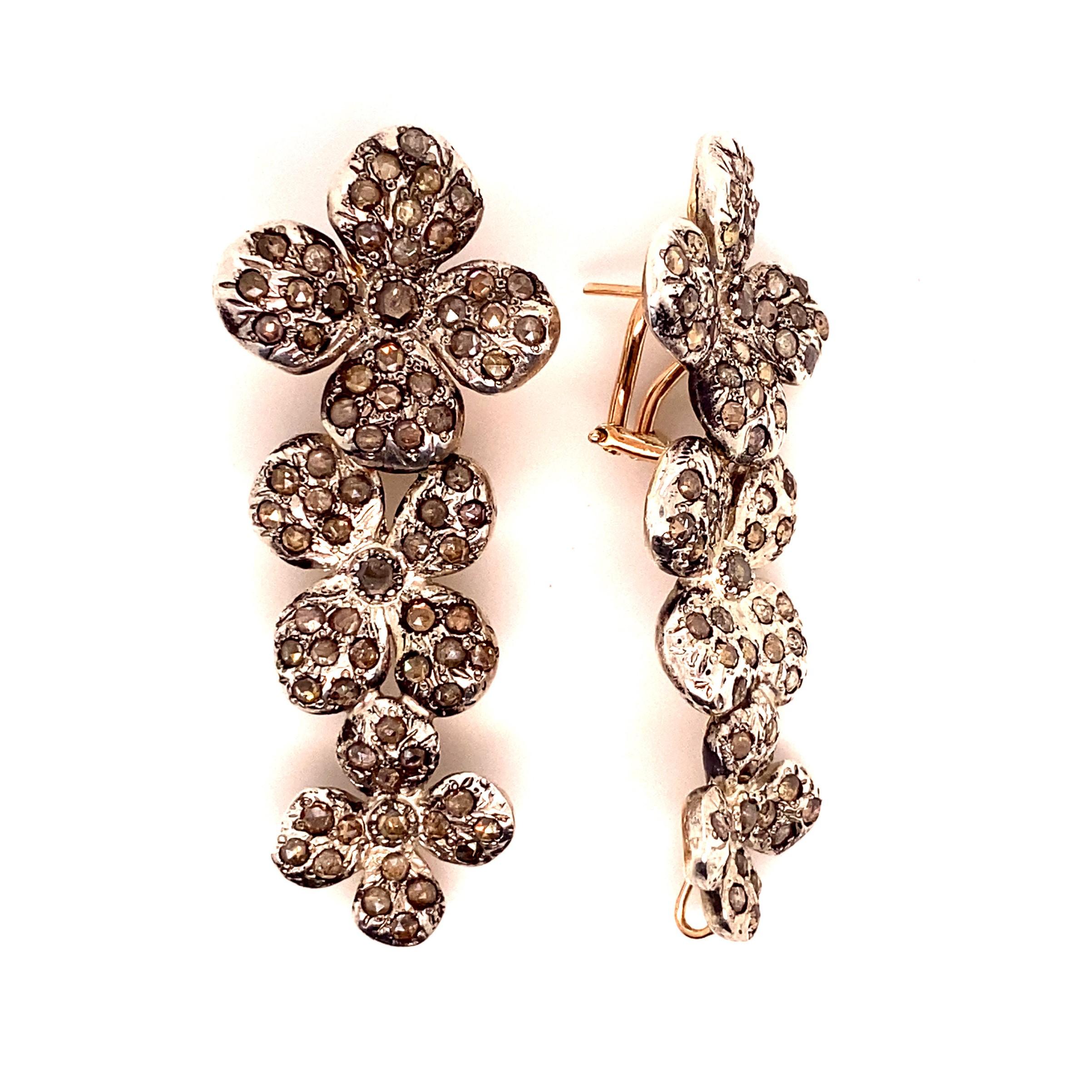 These drop earrings, masterfully created by hand from 9-karat rose gold and 925 silver are each set with a handful of carefully selected rose-cut white diamonds. 

The flowers' central diamonds weigh .70 carats, and the combination of the rest of